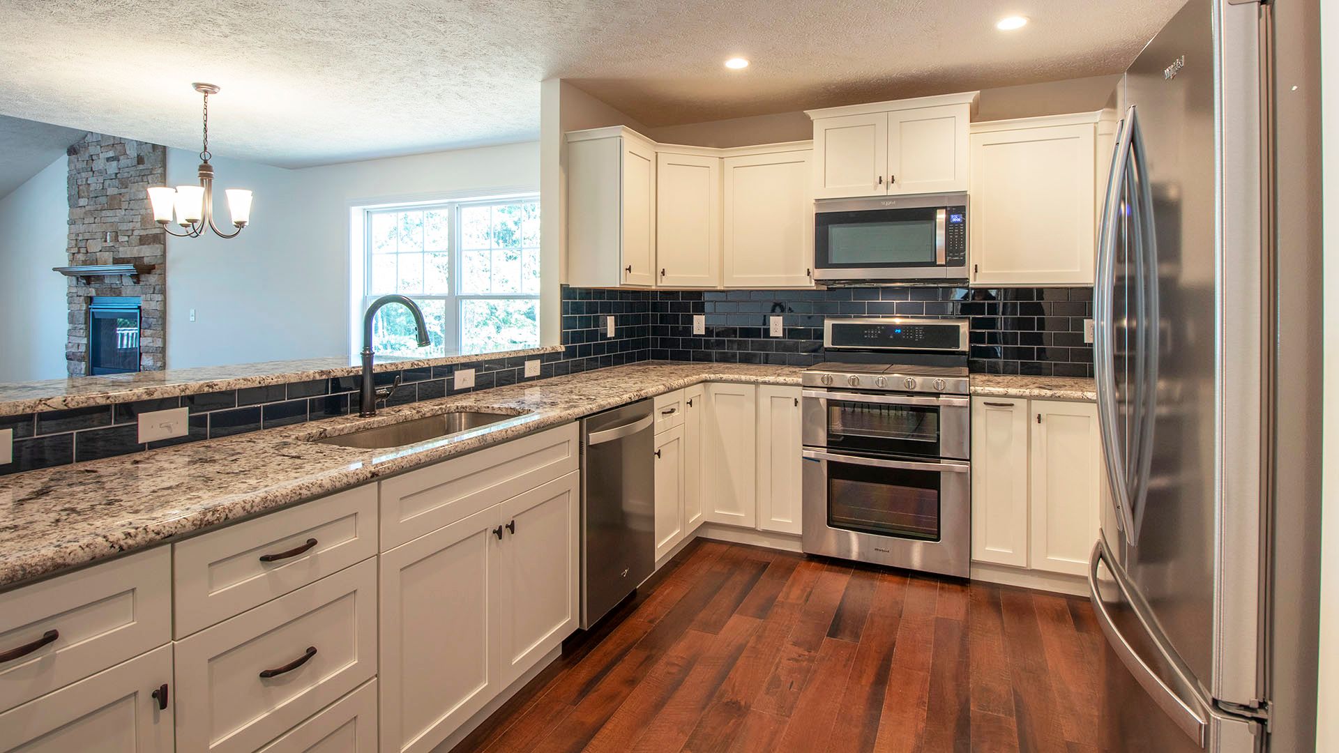 Kitchen with white cabinets, granite countertops and hardwood floors in Aspen plan by S&A Homes