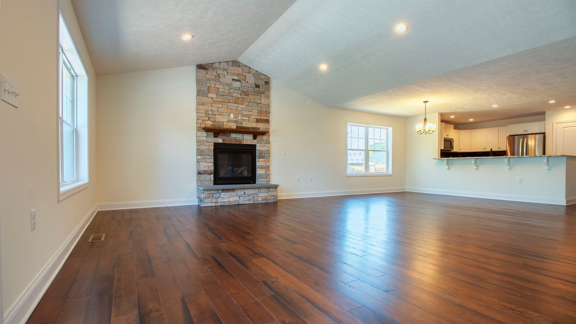 Family room with hardwood floors and fireplace with stone surround, Aspen plan by S&A Homes