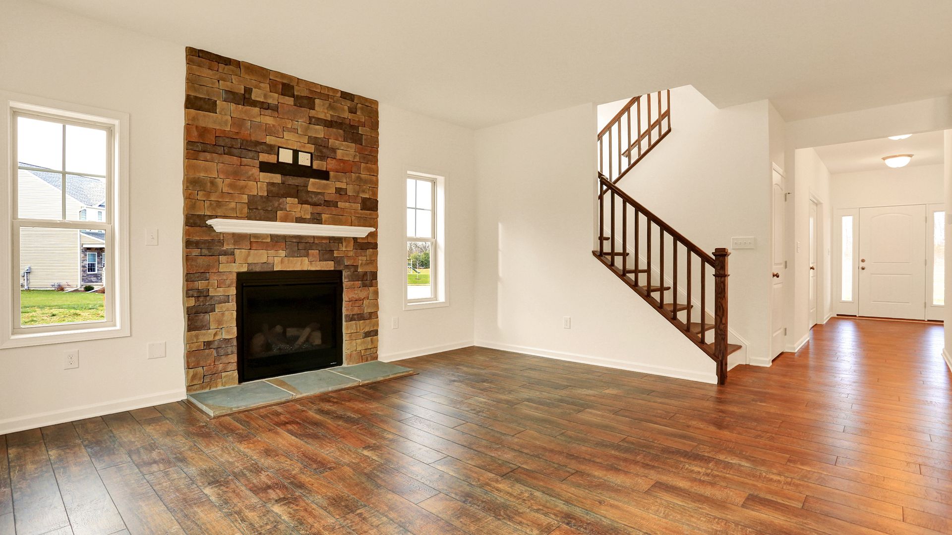 Family room with hardwood flooring, stone fireplace and oak stairs, Fairmont plan by S&A Homes