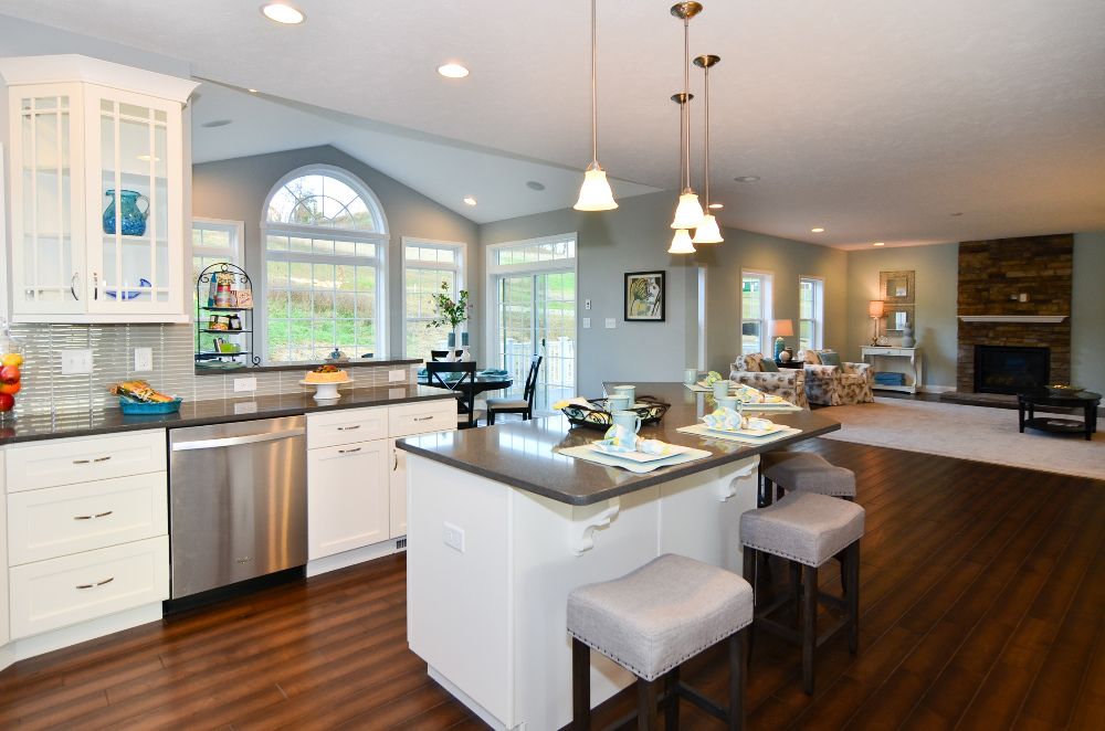 Kitchen with white cabinetry and center island - overlooking rear morning room with wall of windows and furnished family room
