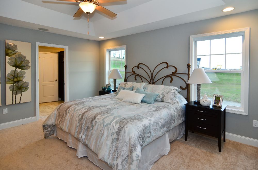 Furnished owner's bedroom with tray ceiling and two windows