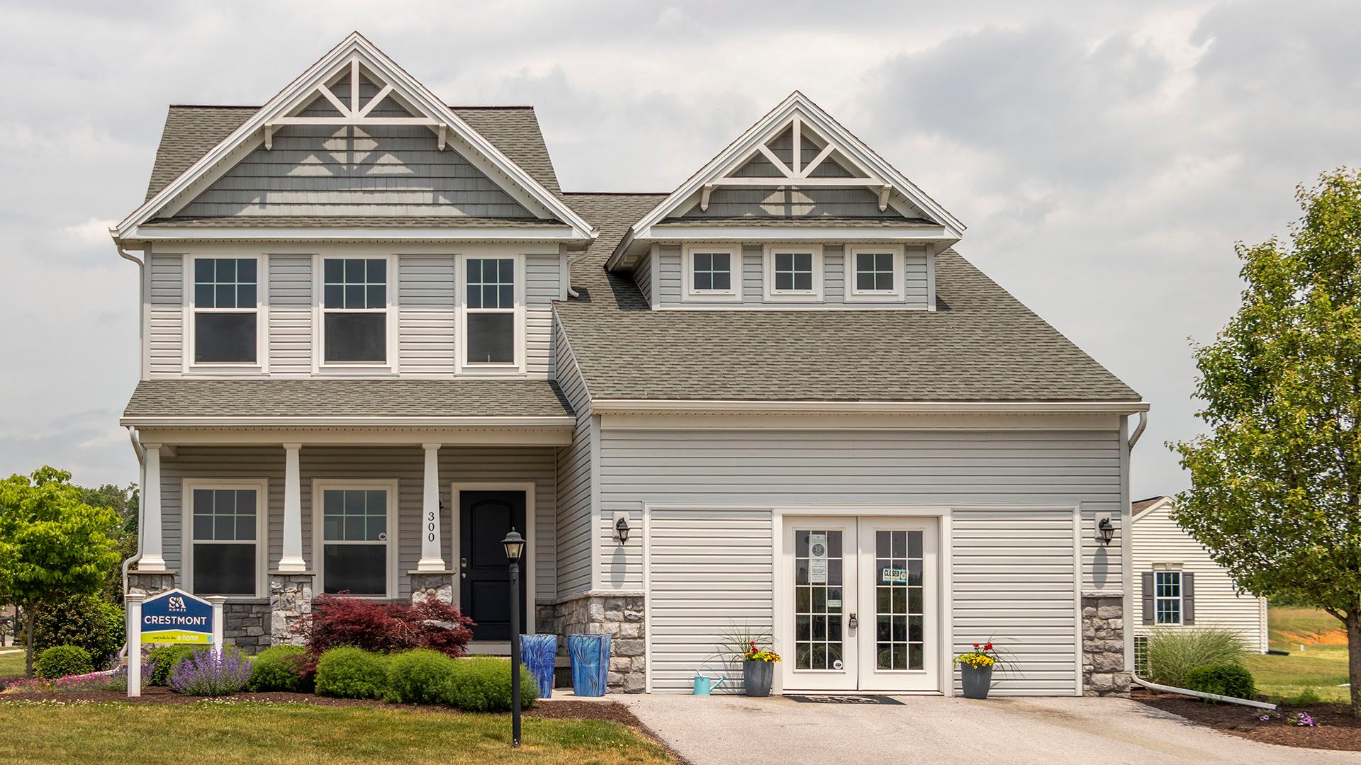 The Crestmont C by S&A Homes - decorated model home at Deerfield in Shippensburg - 2 story home with vinyl siding, covered porch and doorways into garage area.