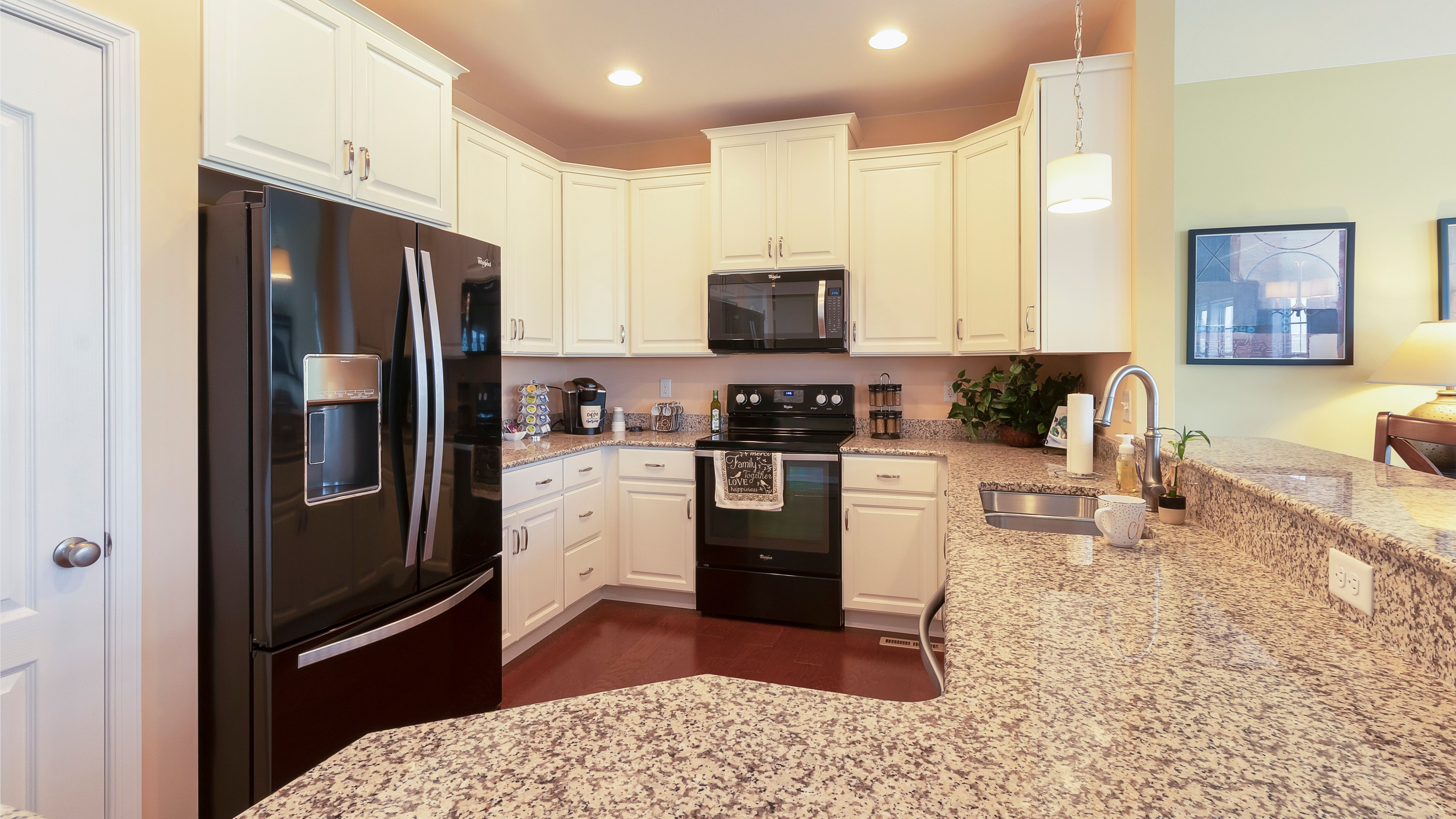 Kitchen with white cabinets, black appliances and granite countertops, Crestmont floorplan by S&A Homes
