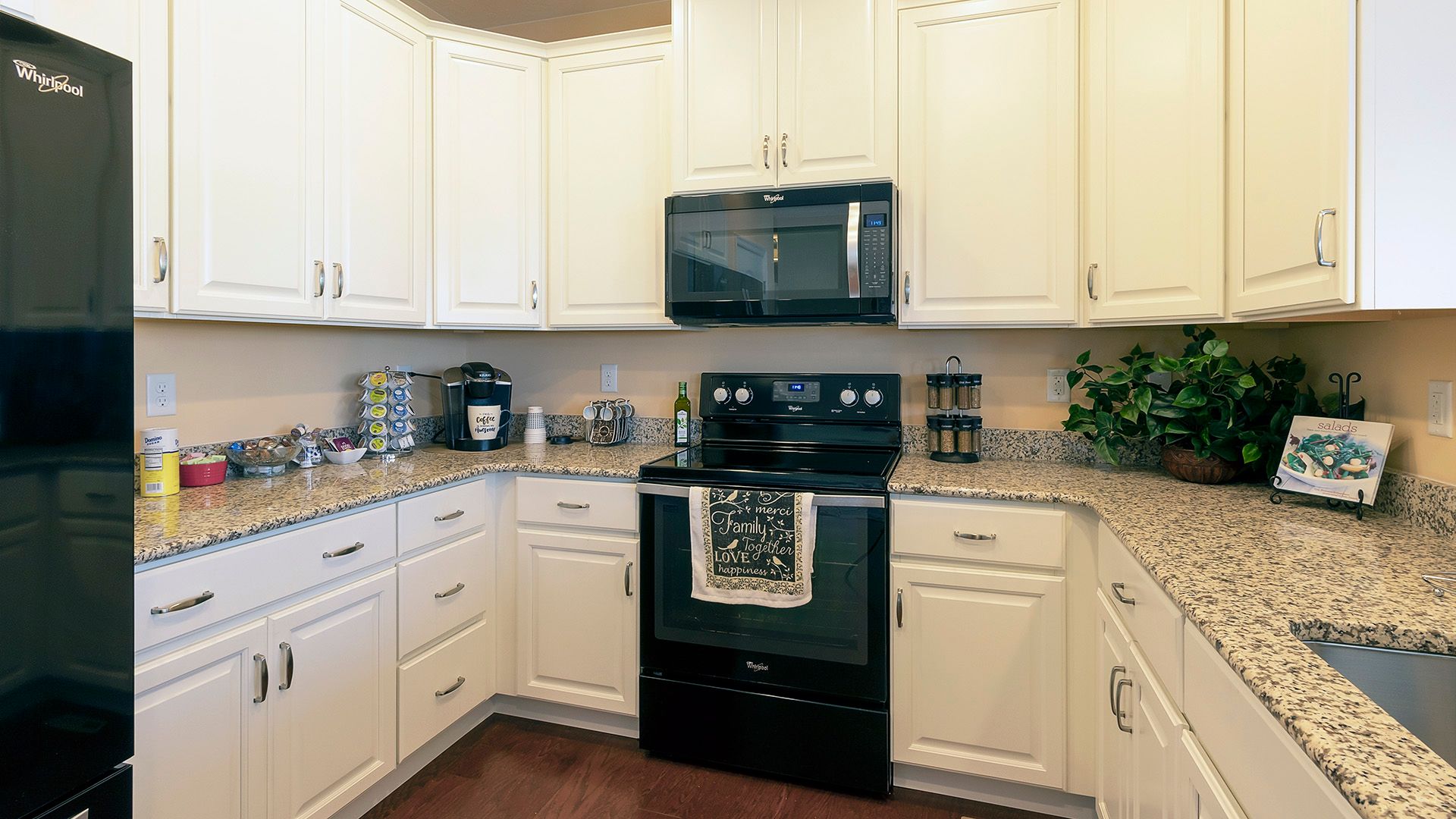Kitchen with white cabinets, black appliances and granite countertops, Crestmont floorplan by S&A Homes