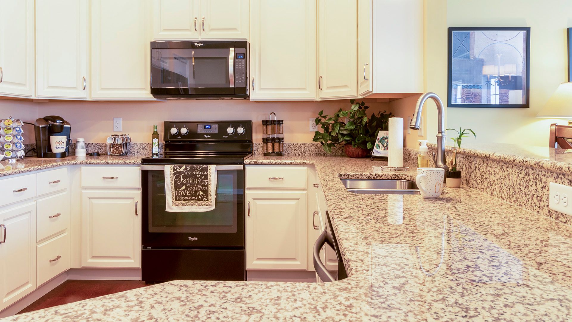 Kitchen with white cabinets, black appliances and granite countertops, Crestmont floorplan by S&A Homes