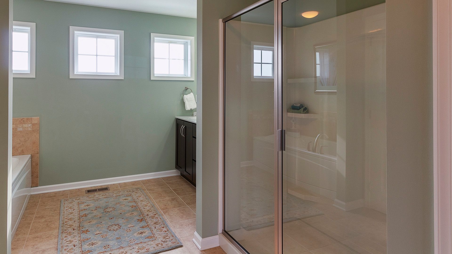 Owners bath with shower stall with glass door, ceramic tile flooring, and three small windows