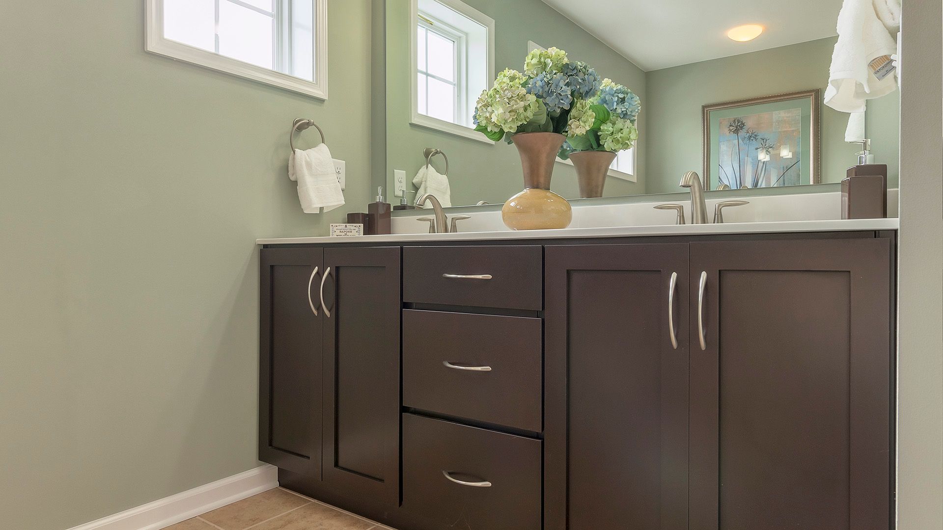 Double bowl vanity with dark cabinets and floral decorations in owners bdroom, Crestmont floorplan by S&A Homes