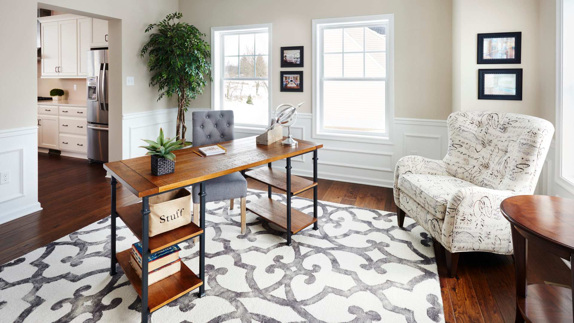 Furnished study with two large windows, hardwood floor and decorative rug