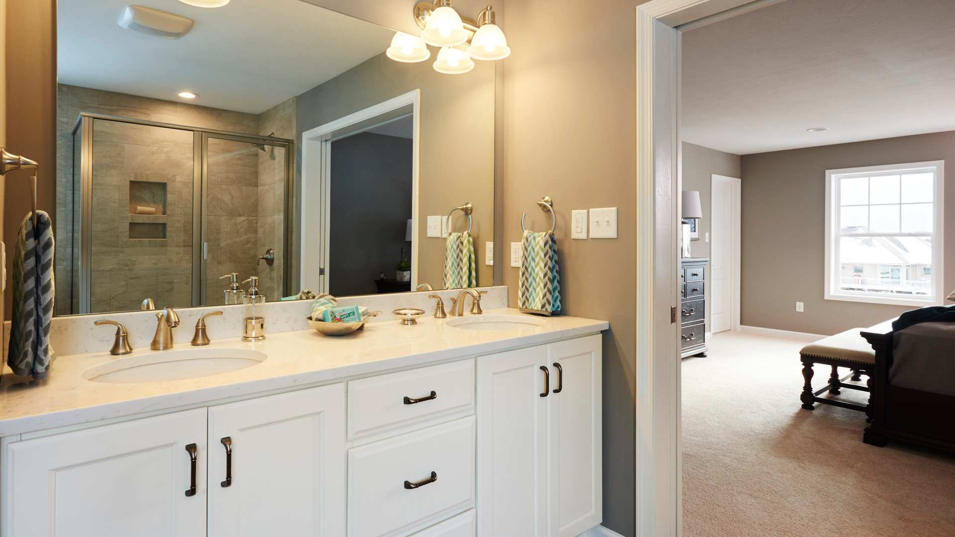 Owner's bath with white vanity cabinets and large mirror above - doorway into owner's bedroom