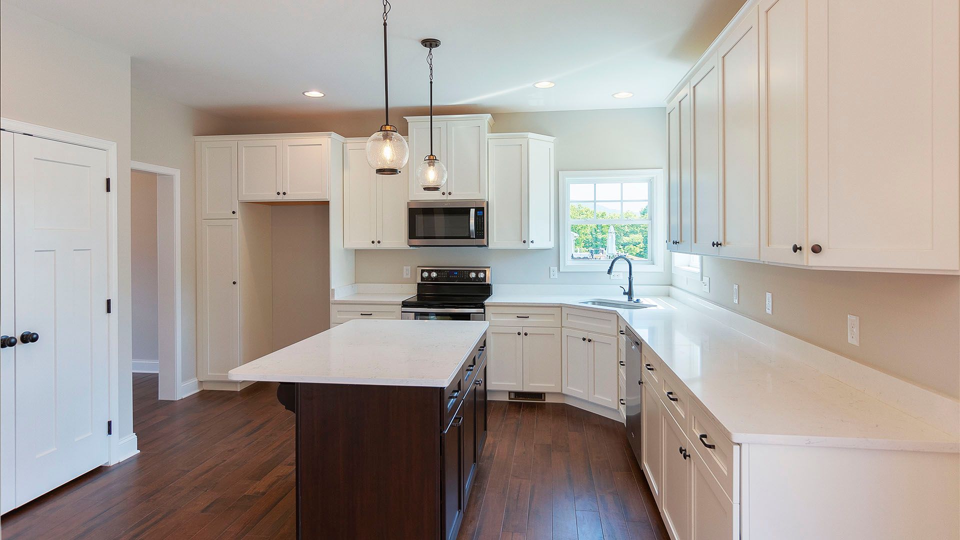 Open Kitchen with white cabinets, large center island, microwave, and oven