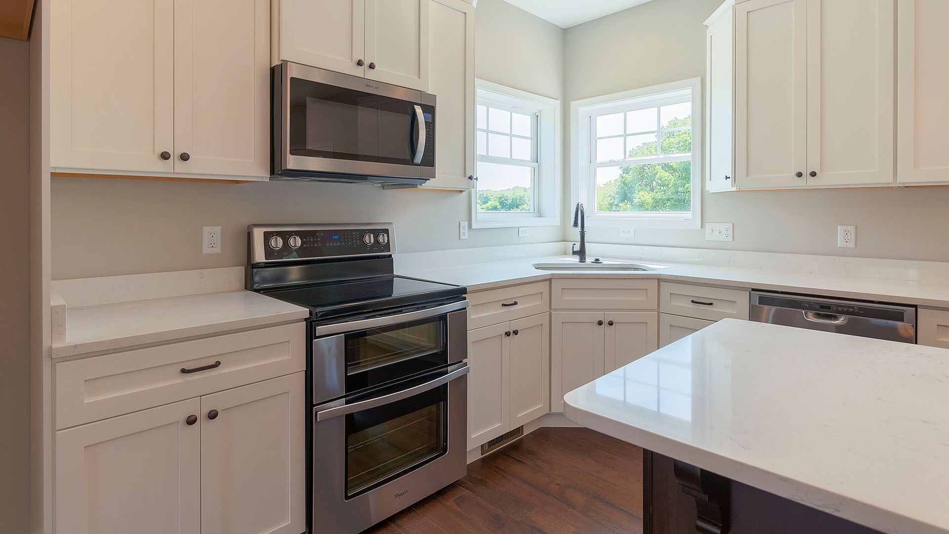 Kitchen with white cabinets, white quartz countertops and stainless appliances.