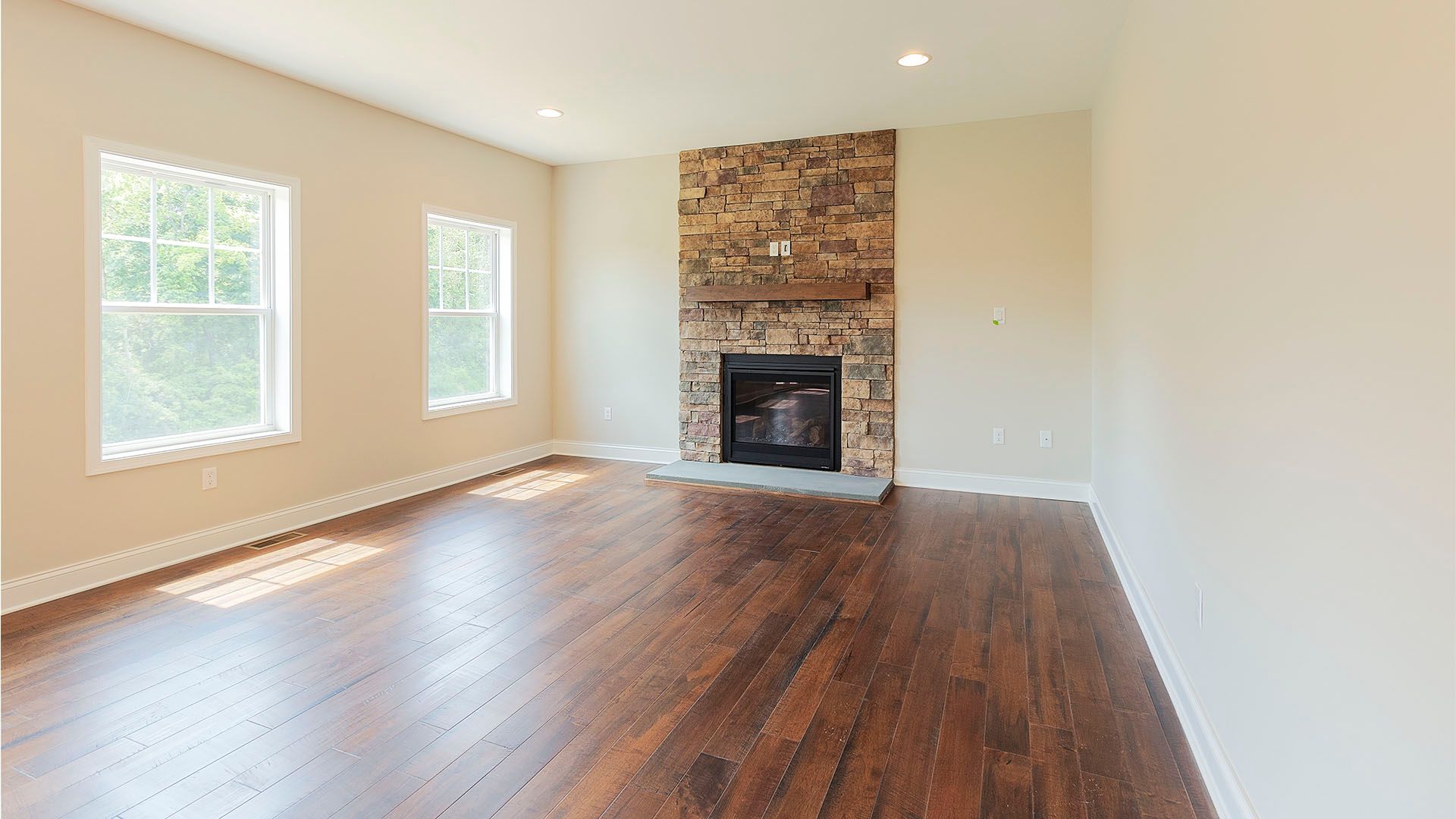Great room with 2 windows, stone fireplace, white walls