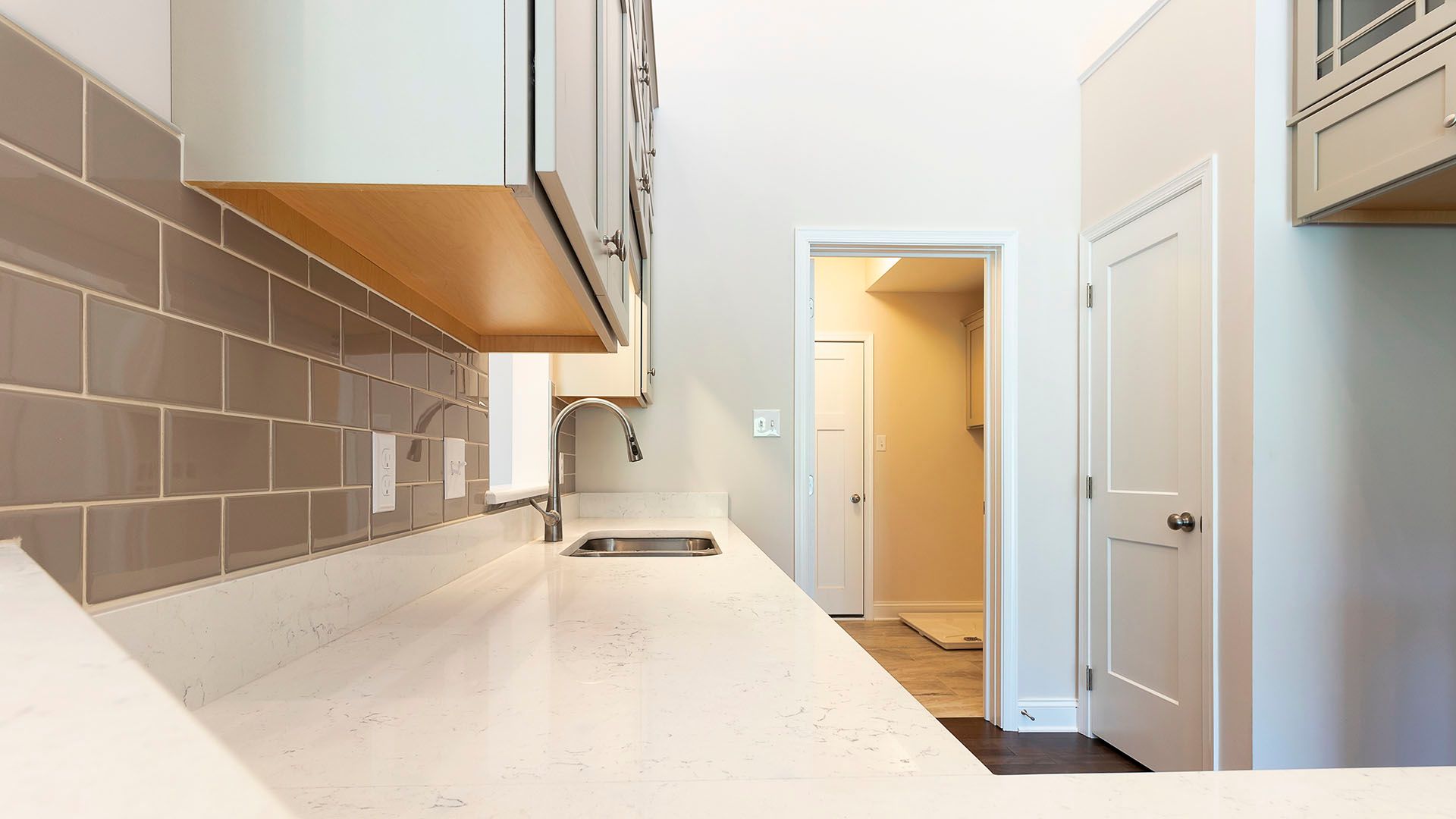 White quartz countertops with tan backsplash and tan upper cabinets, Chilton plan