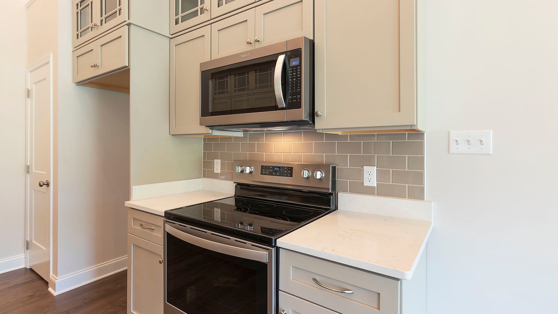 Stainless steel electric range, microwave, and white cabinets