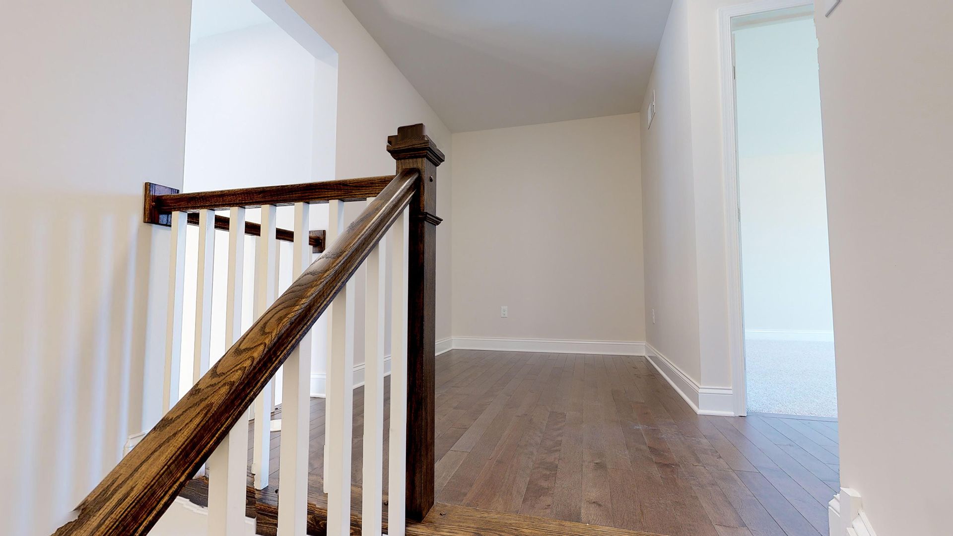 Stairs to second floor loft area with oak handrails and white balusters, and hardwood flooring in loft