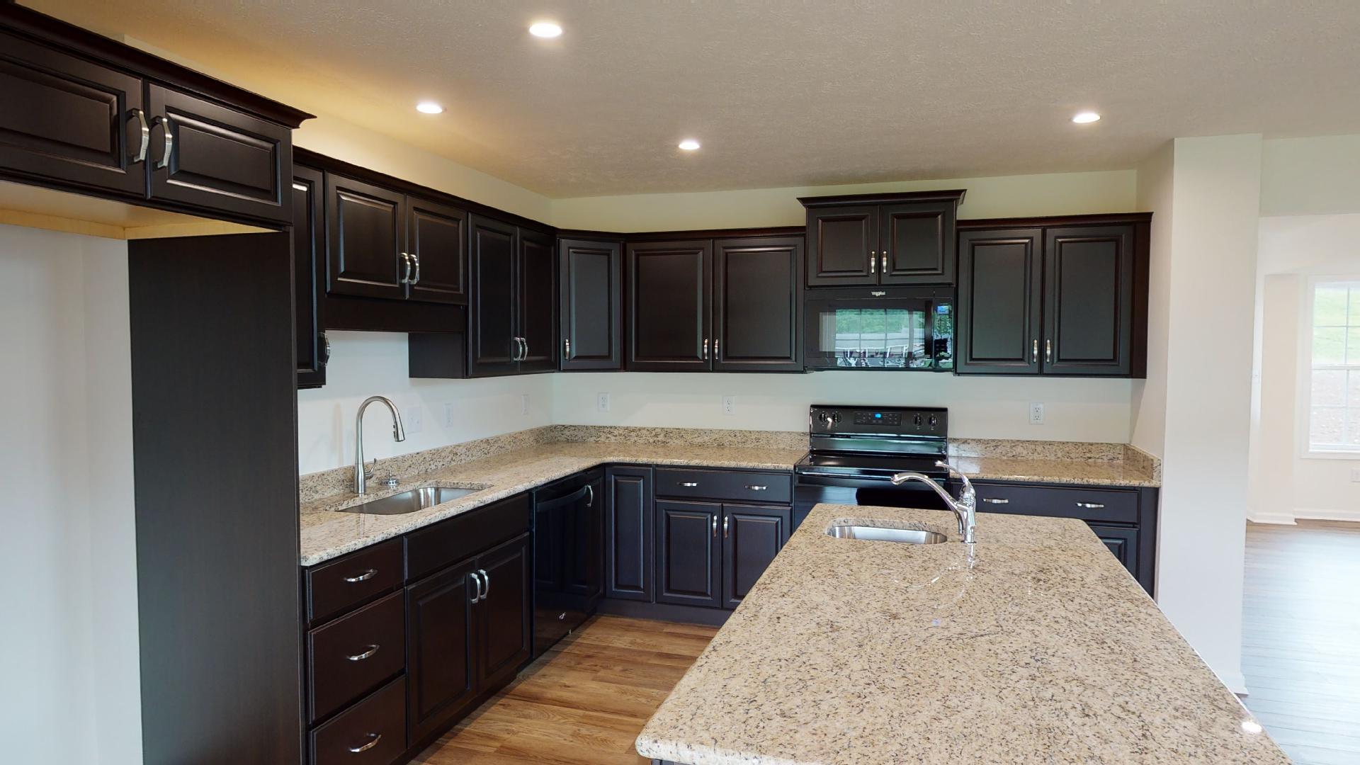 Kitchen with dark cabinetry, center island, granite countertops and black appliances.