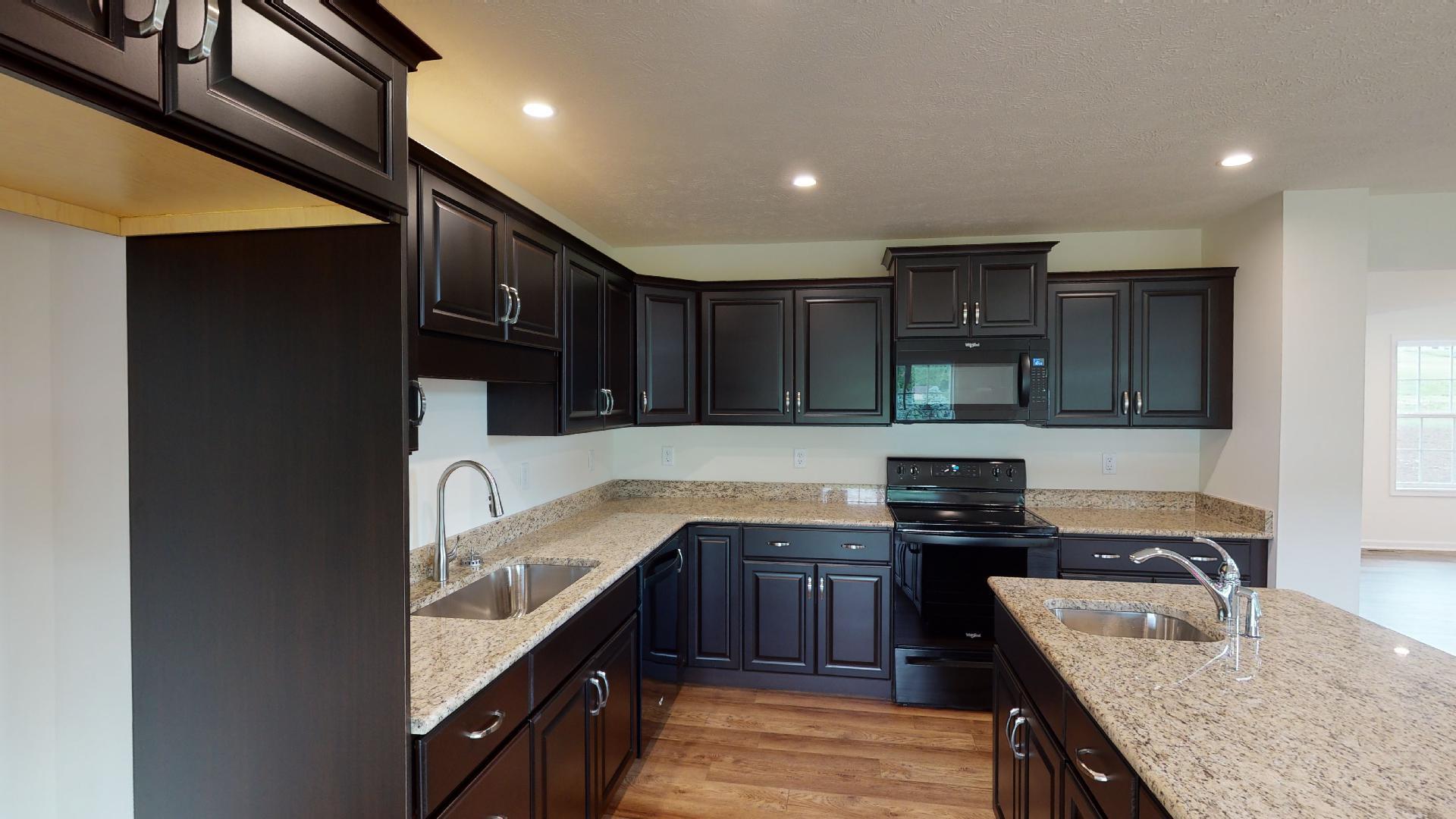 Kitchen with dark cabinetry, center island, granite countertops and black appliances.