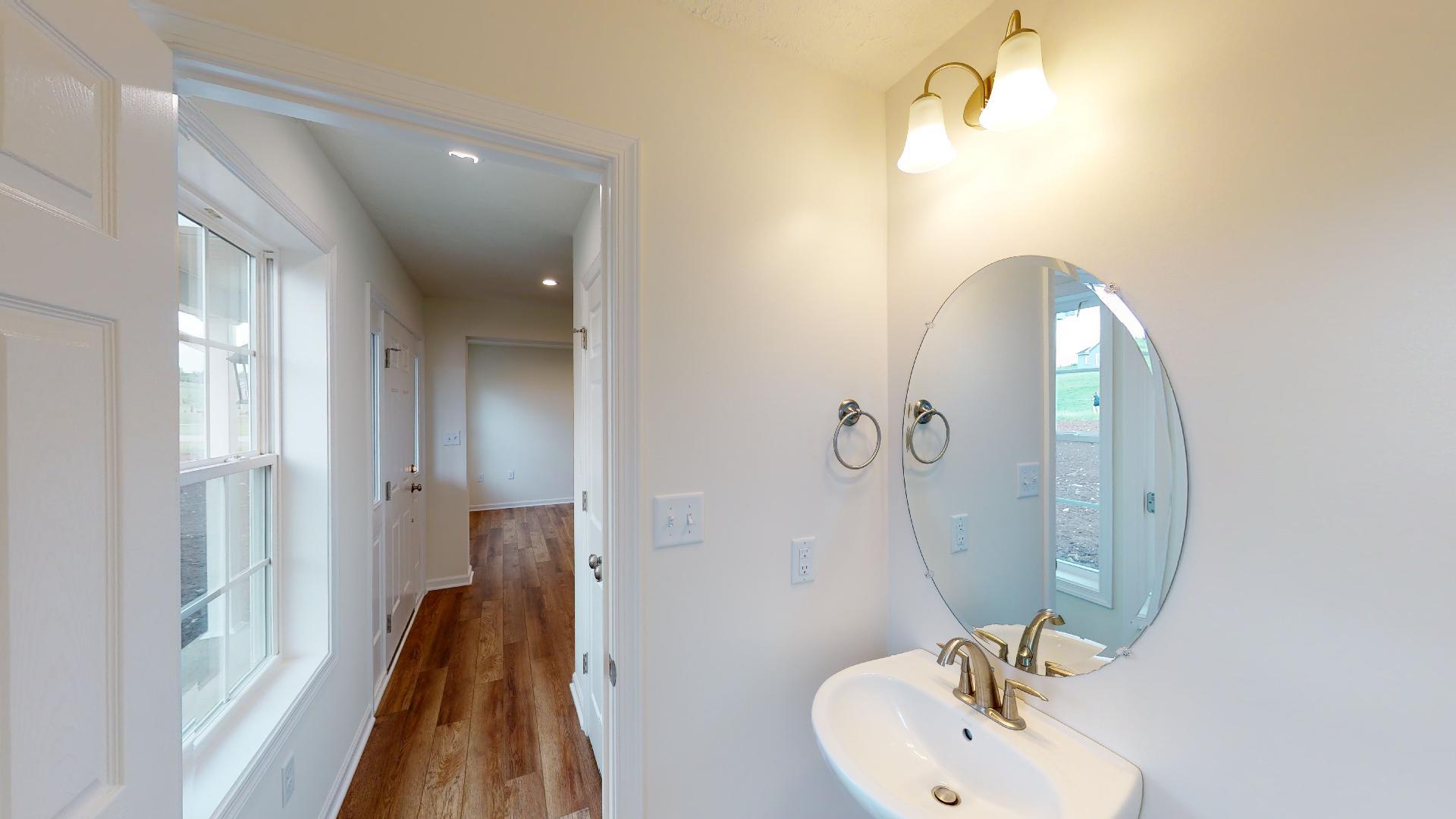 Powder room with pedestal sink and oval mirror above