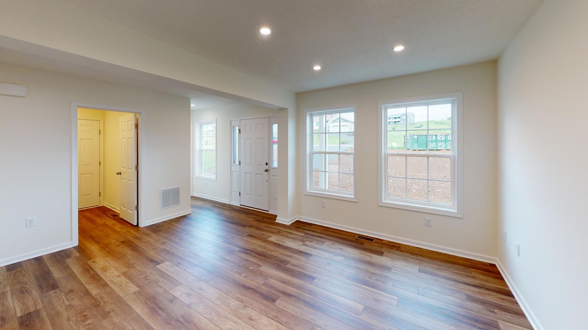Foyer and living room area with windows on front wall and vinyl plank flooring