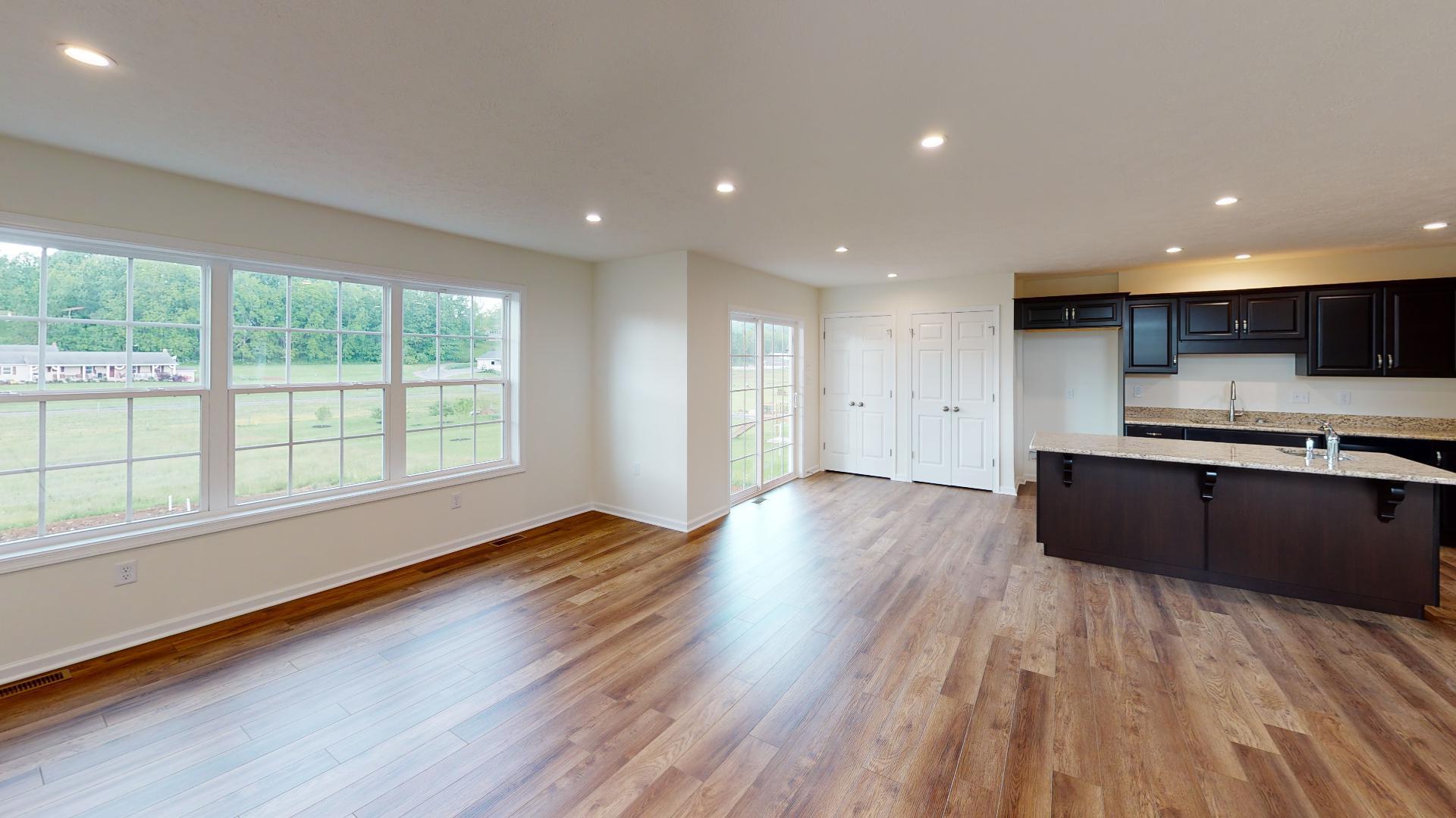 Family room, dining area and kitchen - 3 windows on the back wall of the family room, and a sliding glass door - vinyl plank flooring