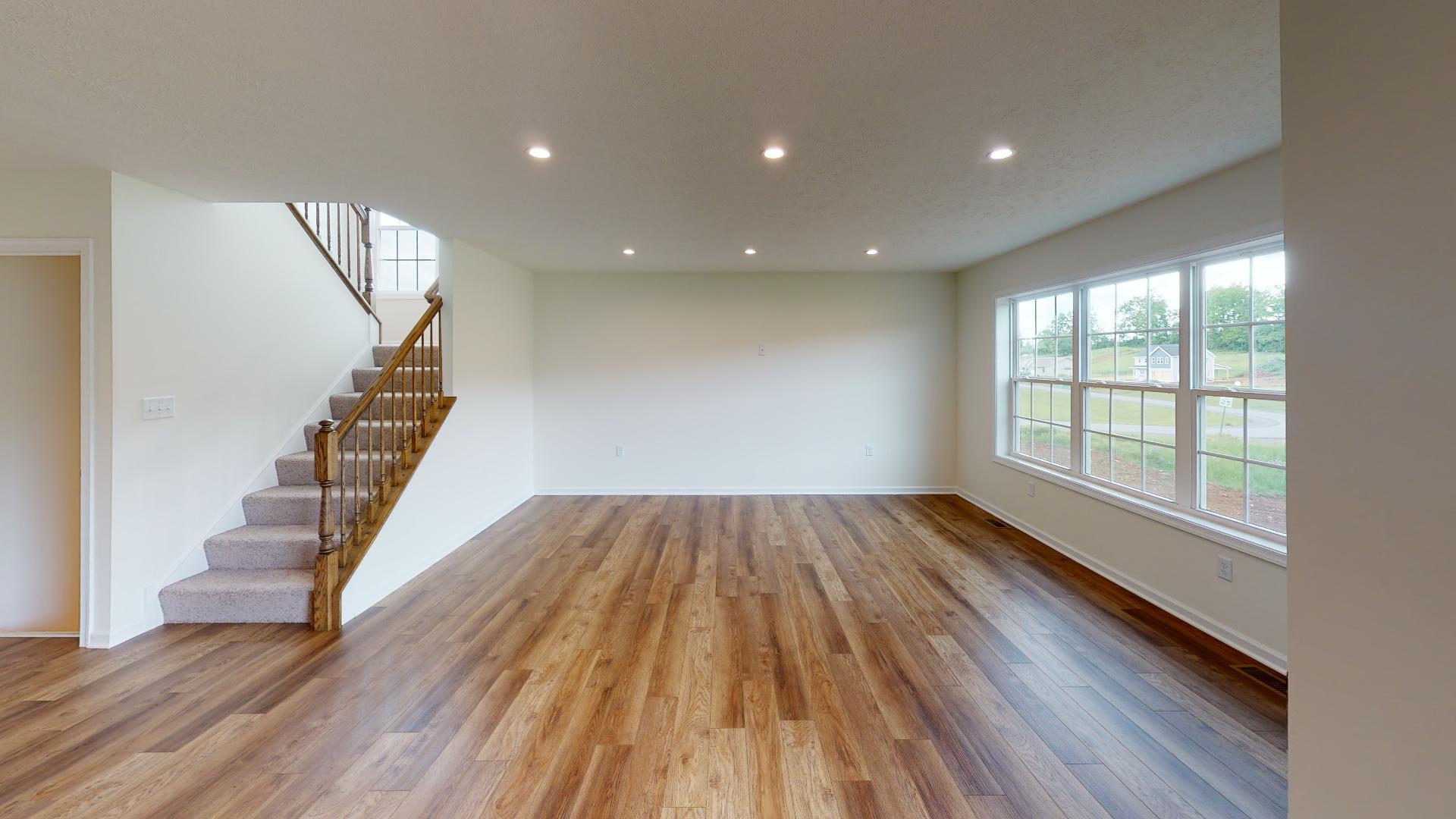 Family room and staircase to the 2nd floor - triple windows on the back wall and vinyl plank flooring throughout