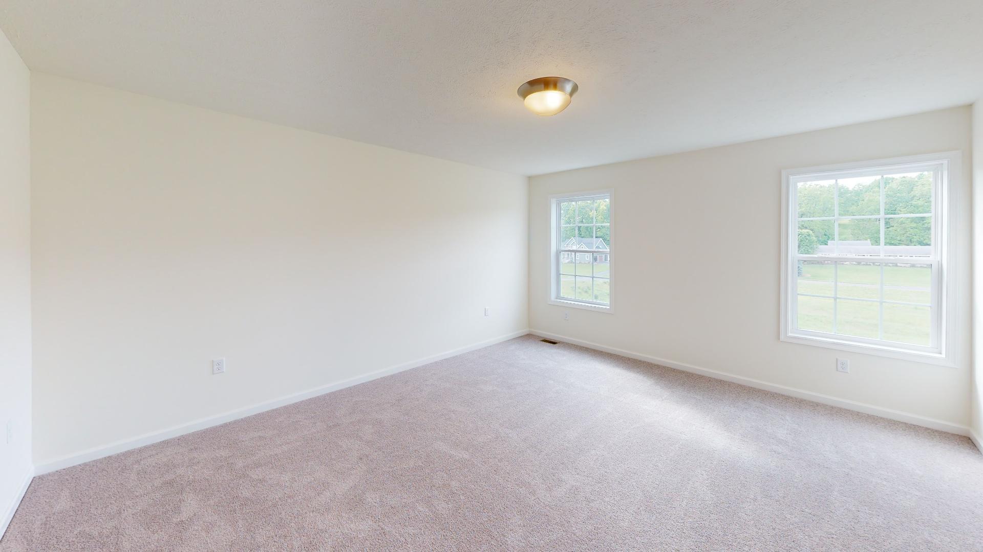 Owner's bedroom with two windows on rear wall and carpet flooring