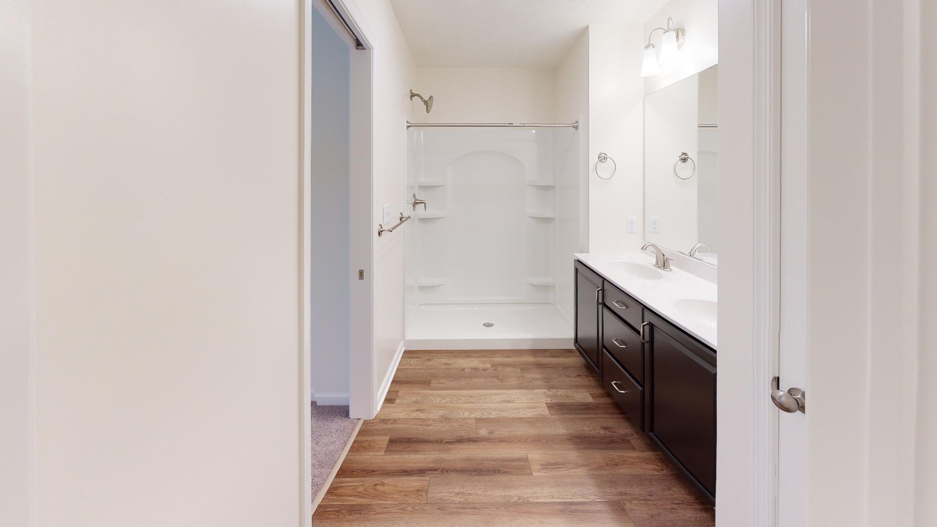 Owner's bath - shower stall with corner shelves and double bowl vanity with mirror above
