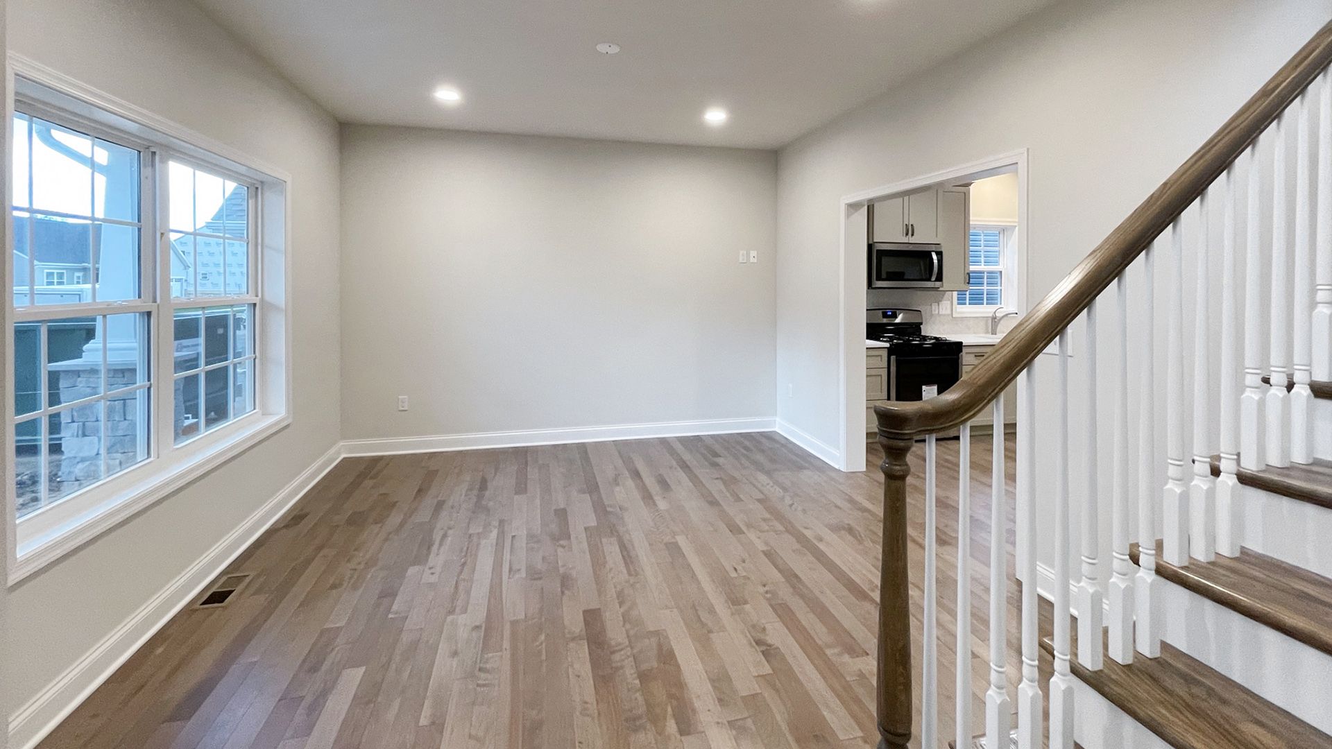 Dining room with two windows on the front wall, foyer to the left - hardwood flooring - entrance to kitchen on the right