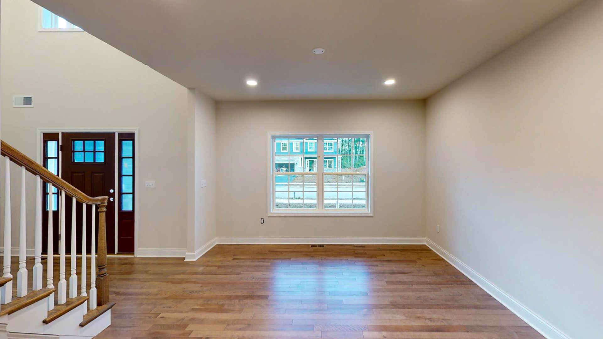 Dining room with two windows on the front wall, foyer to the left - hardwood flooring
