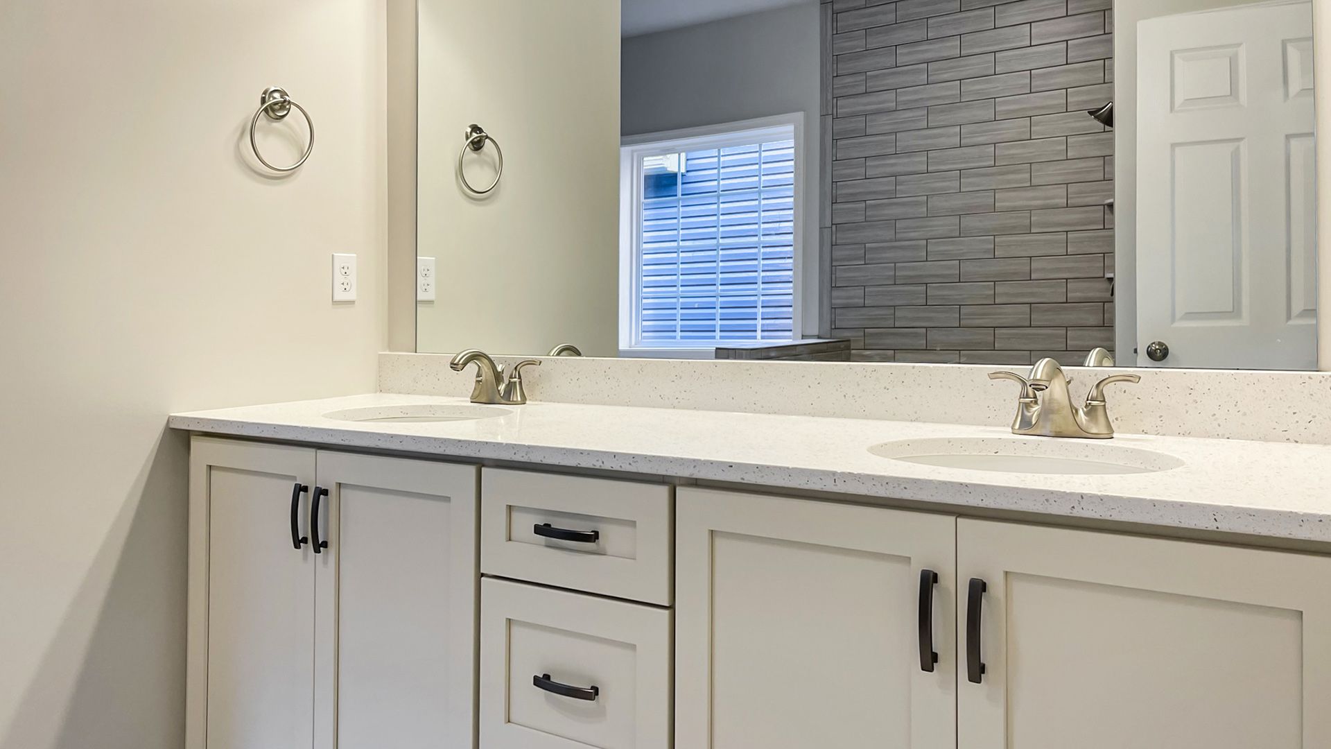Owner's Bath with white cabinetry, double vanity with large mirror above,