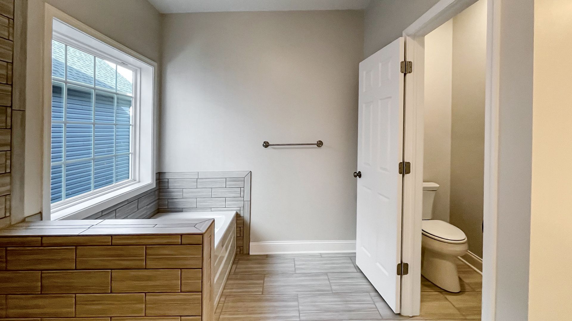 Soaking tub with large window above - across from entry to water closet with toilet.