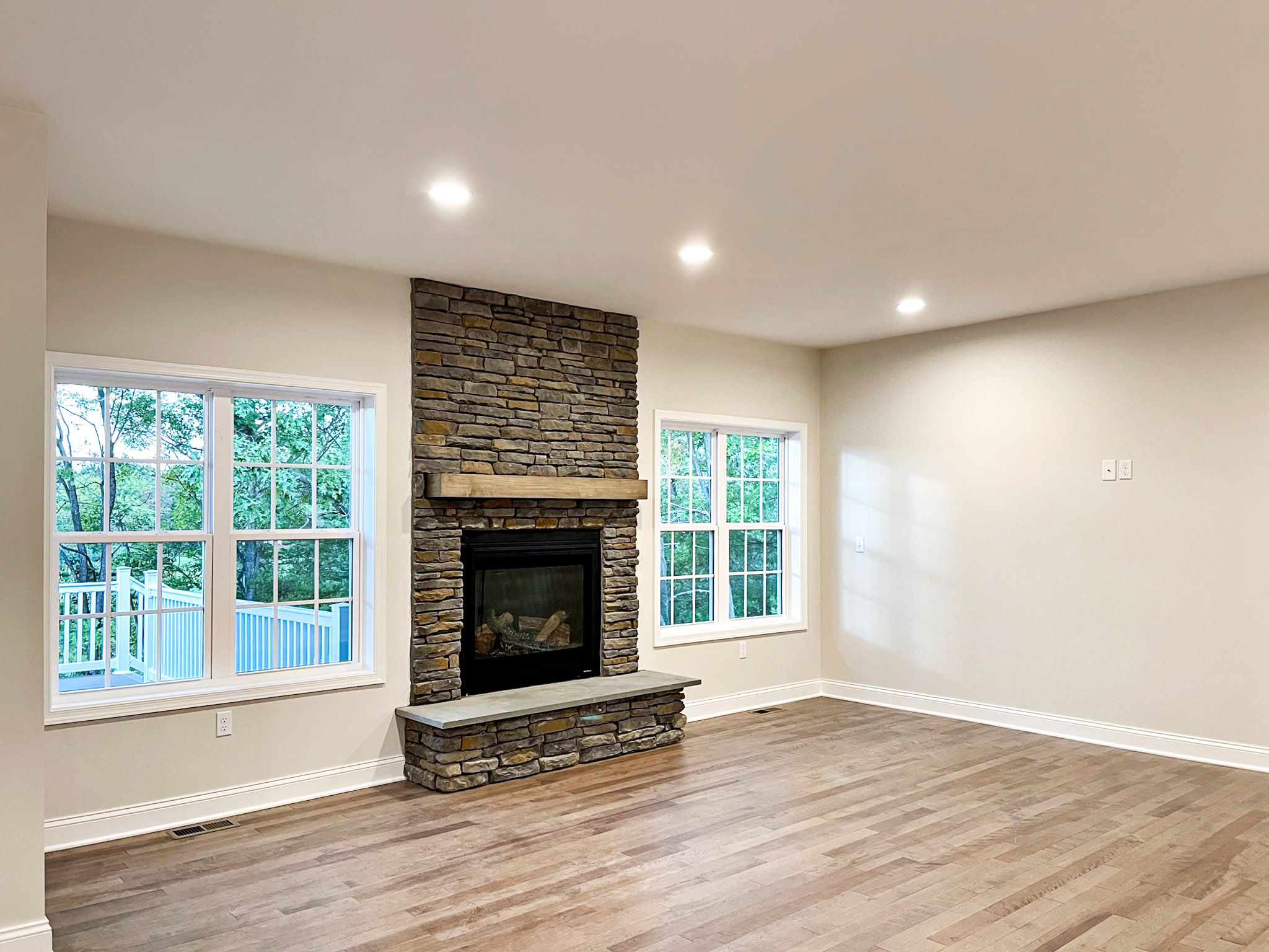 Gas fireplace with raised hearth, stone surround and dual windows on each side.