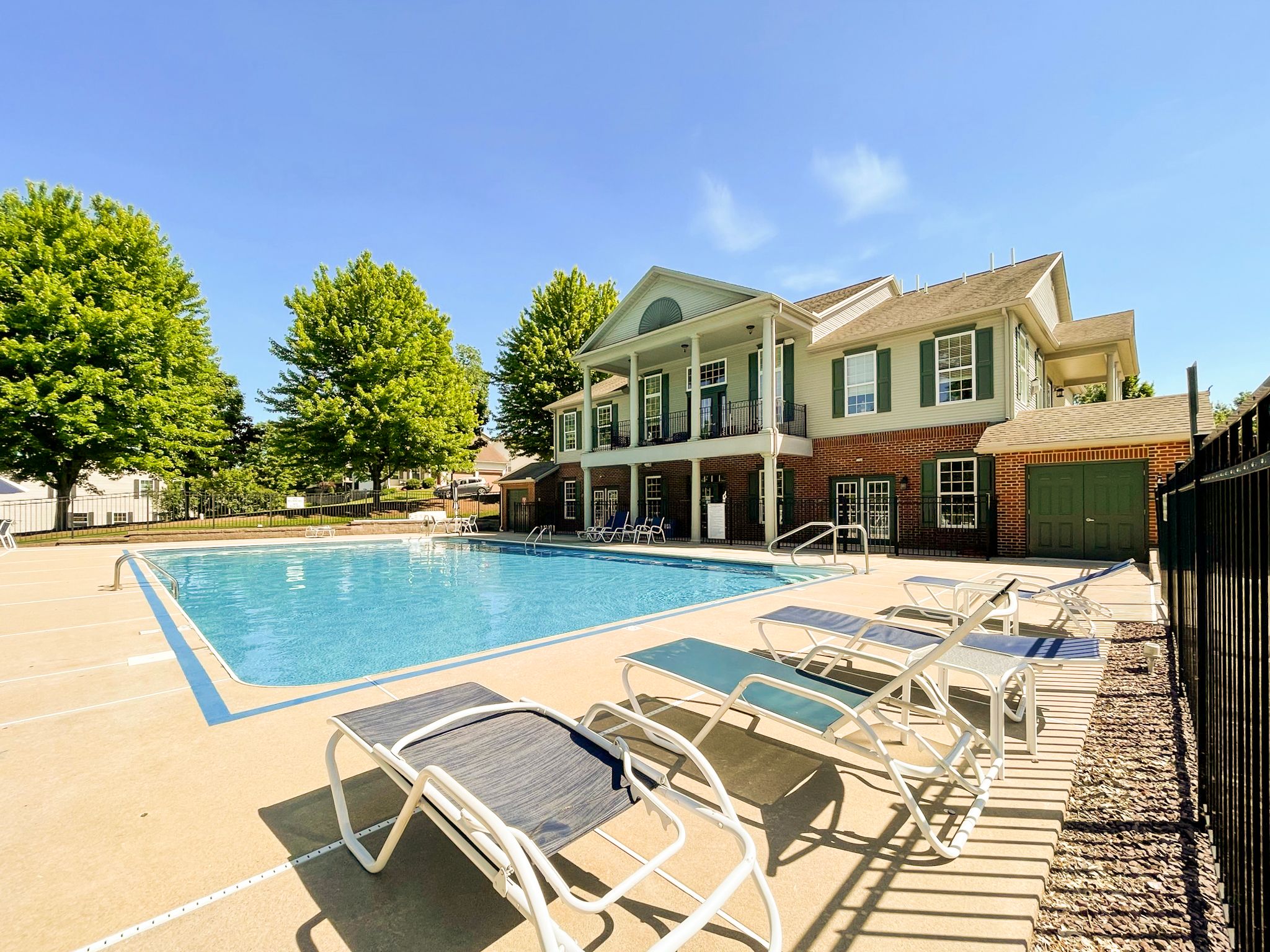 Clubhouse and in-ground pool with chairs in the foreground
