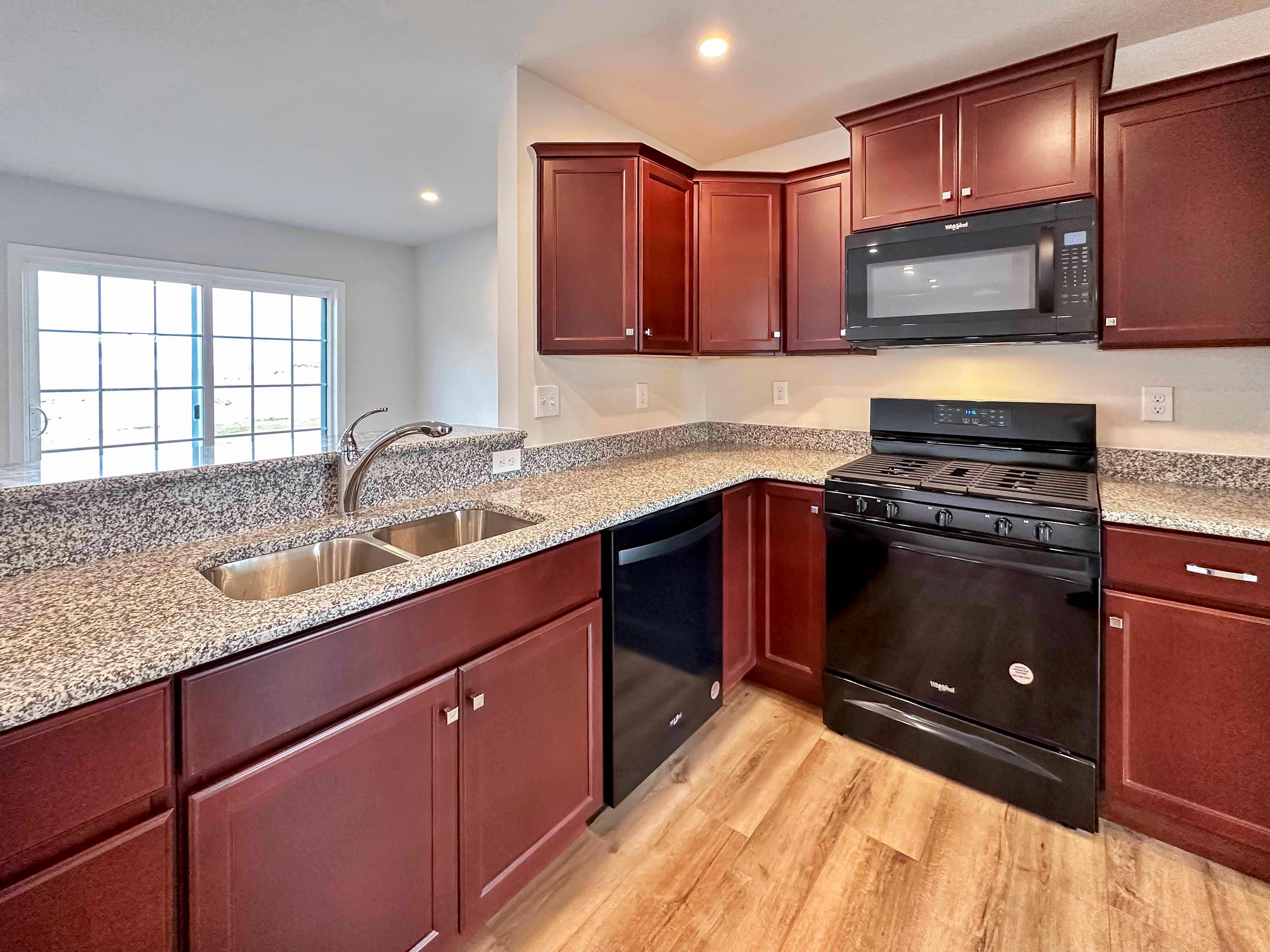 Kitchen with maple cabinets, granite countertops and black appliances