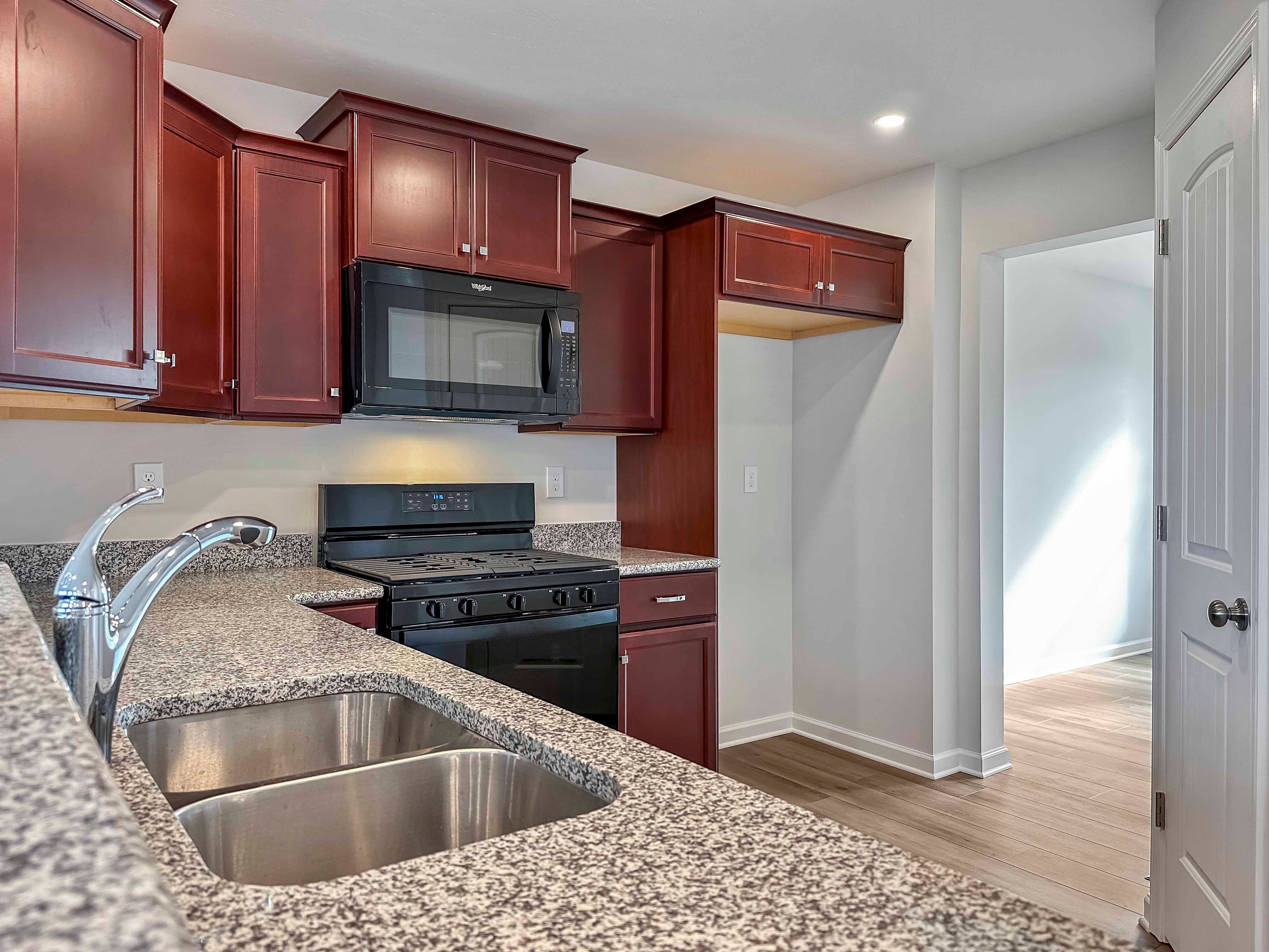 Kitchen with maple cabinets, granite countertops and black appliances