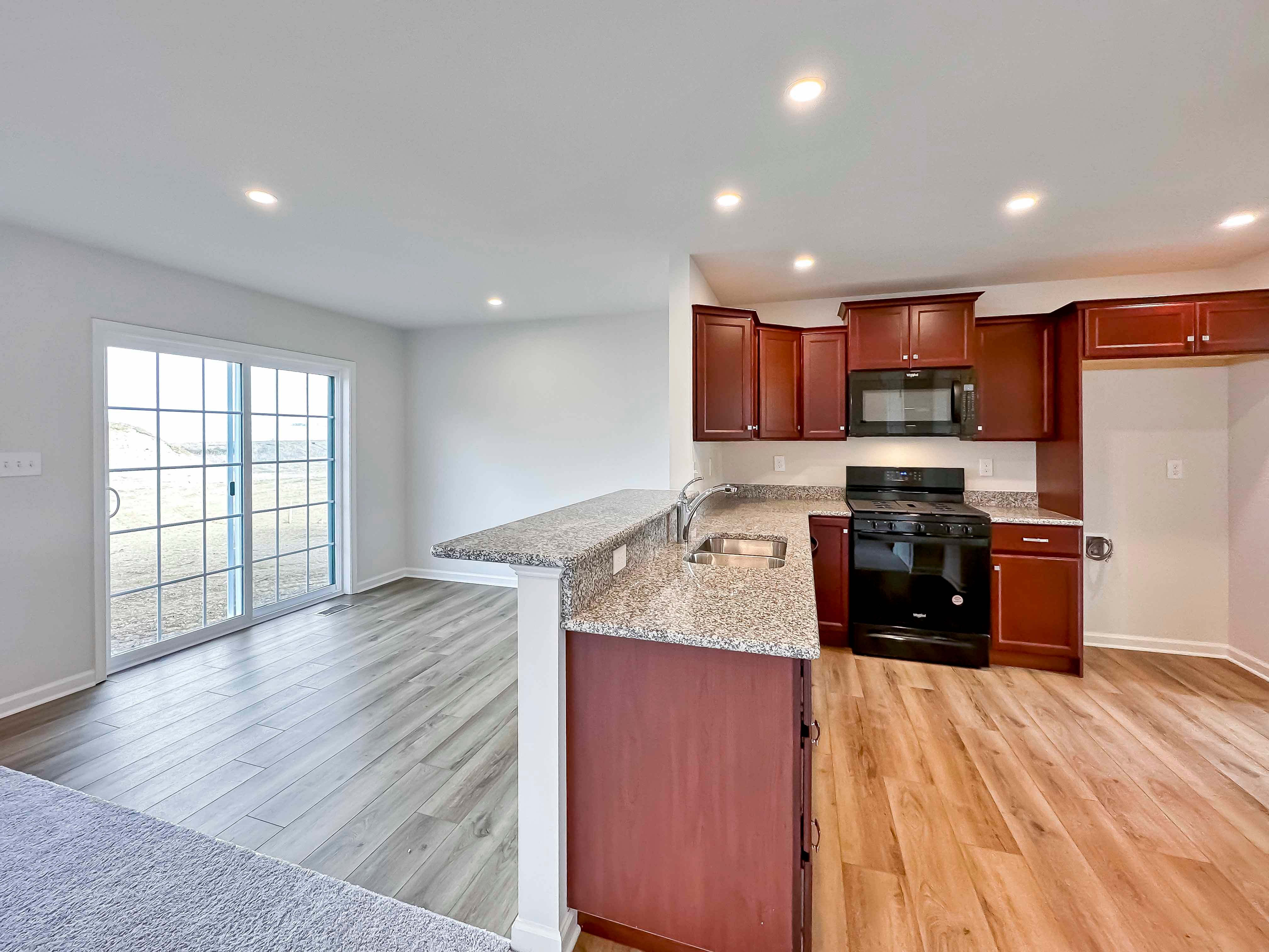 Kitchen with maple cabinets, granite countertops and black appliances