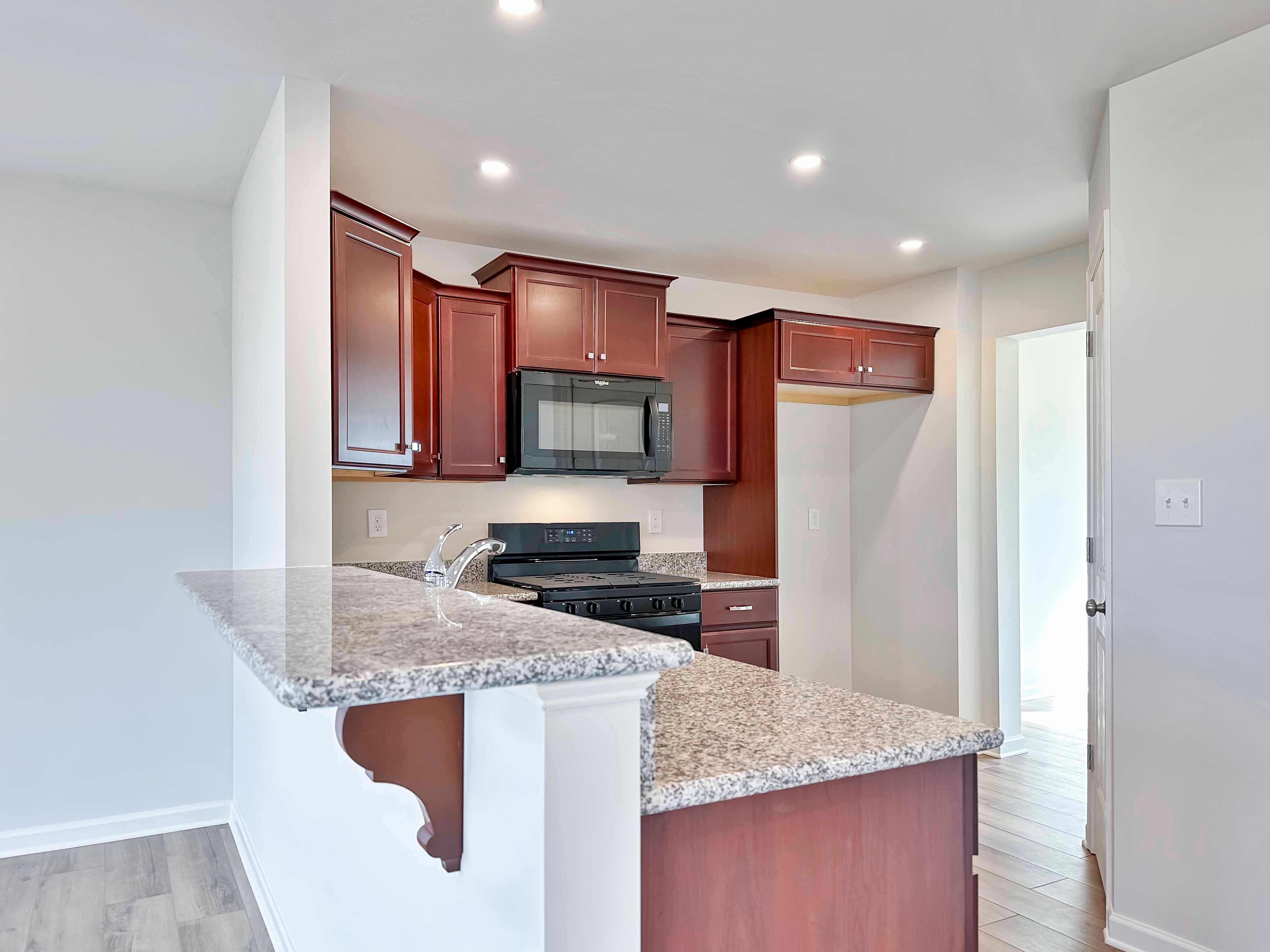 Kitchen with maple cabinets, granite countertops and black appliances