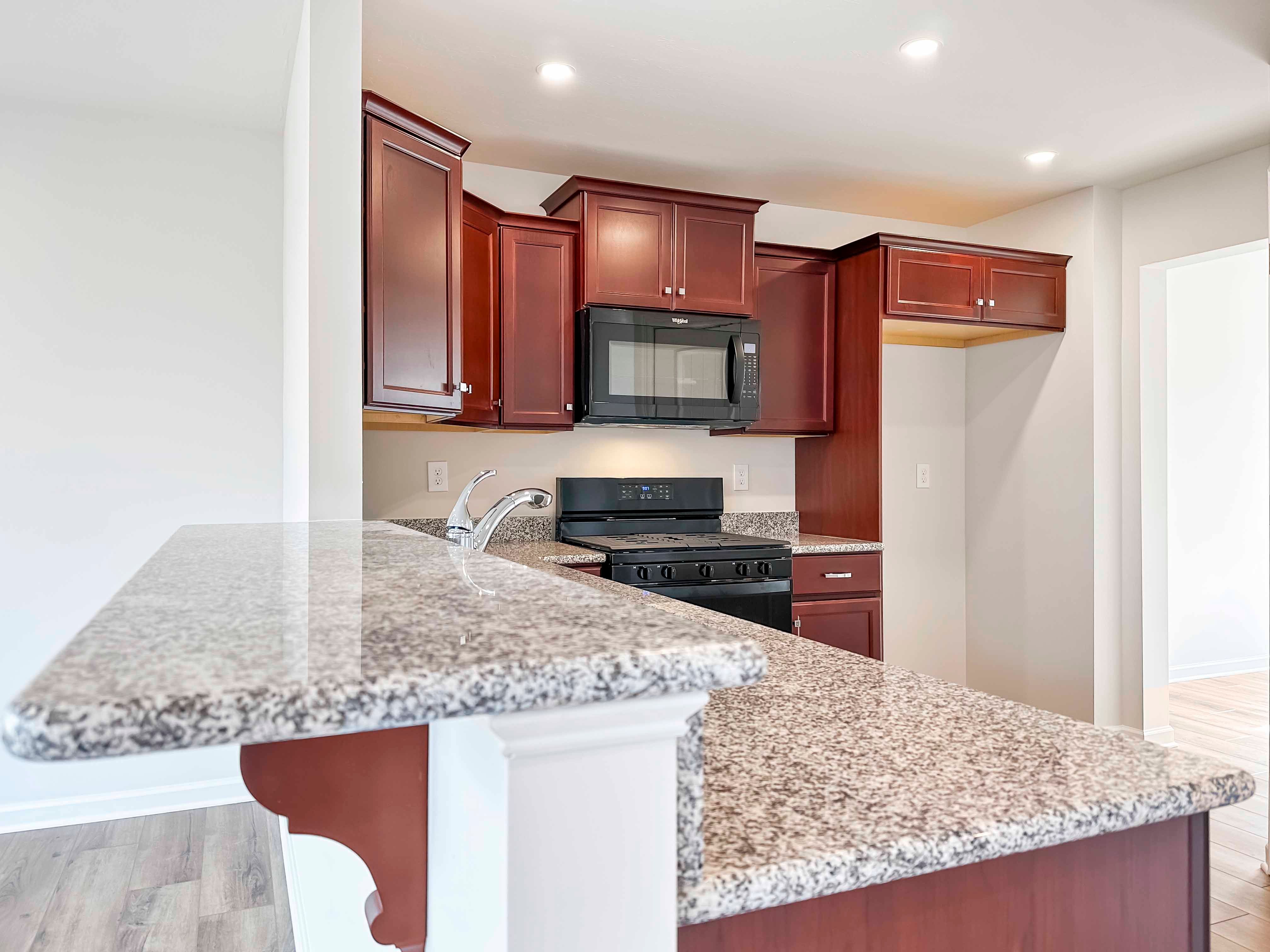 Kitchen with maple cabinets, granite countertops and black appliances