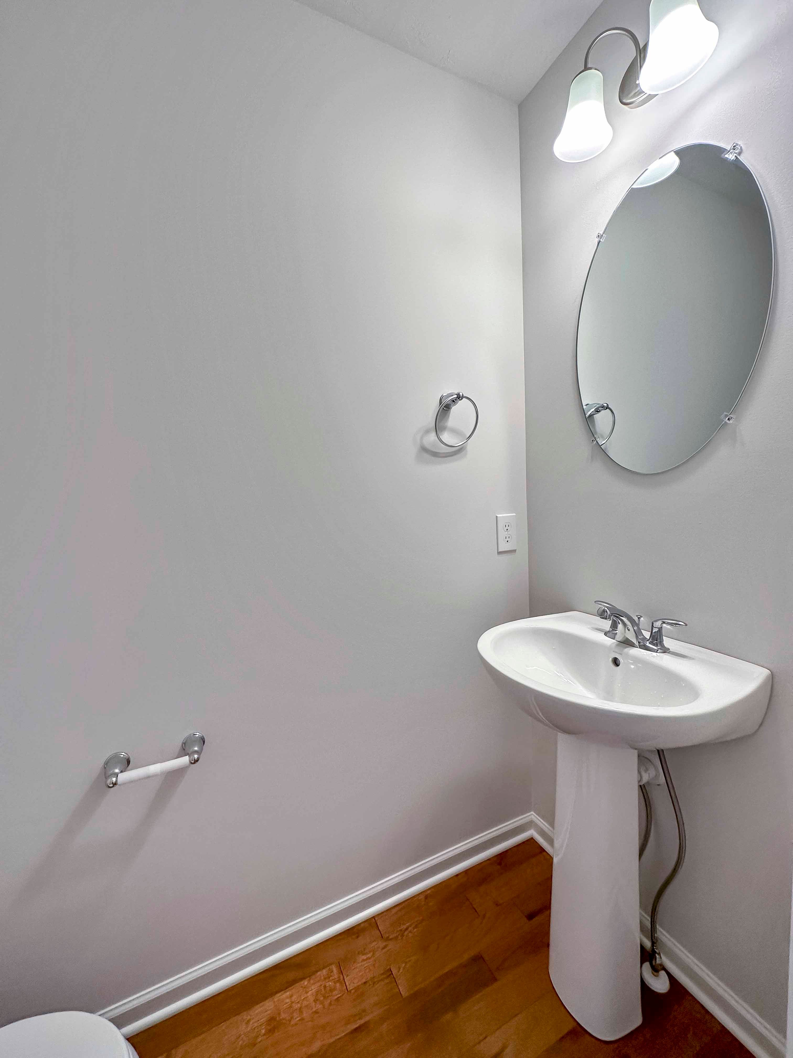 Powder room with pedestal sink and oval mirror