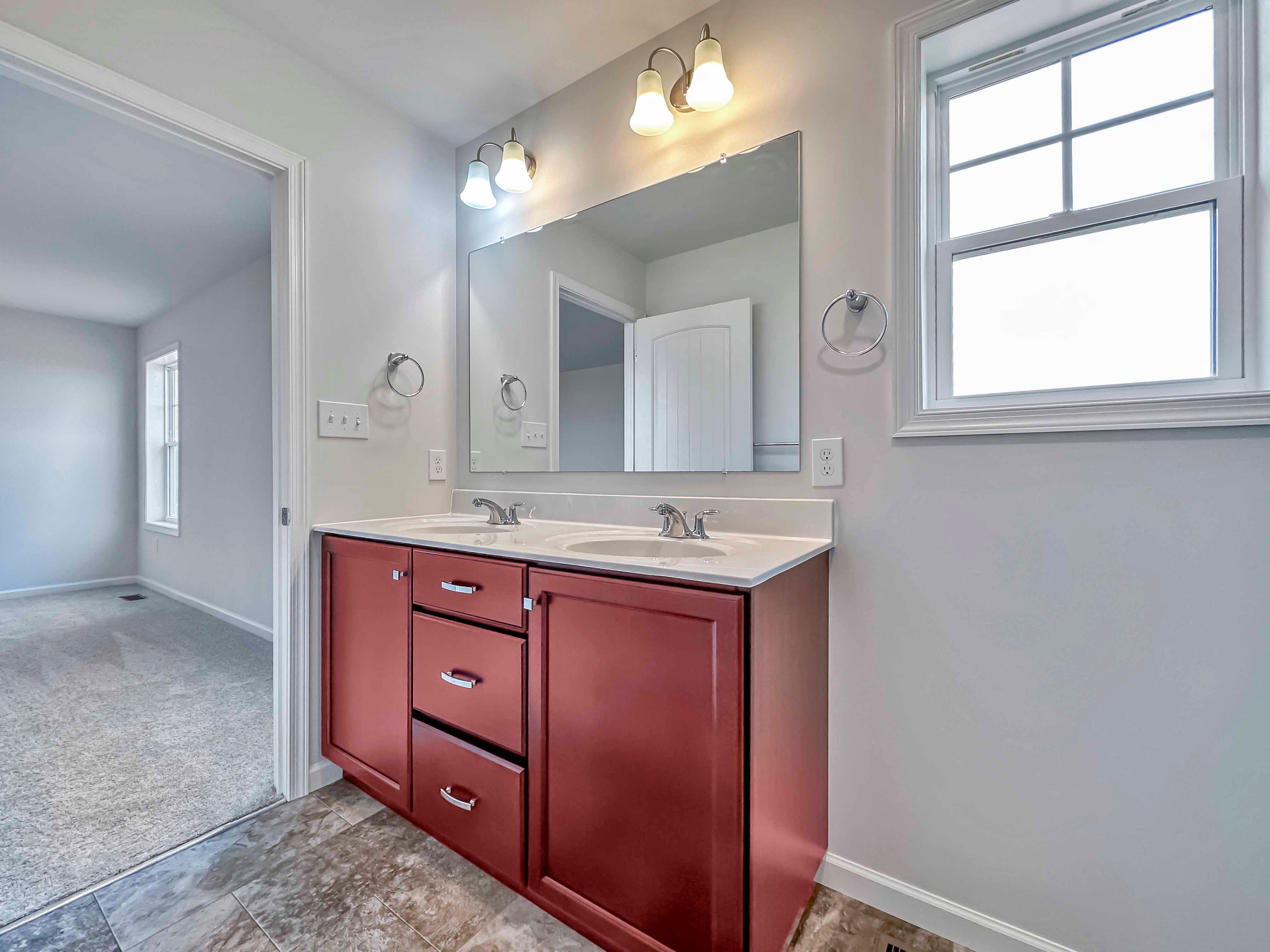Owner's bath with maple vanity, large mirror, and window on rear wall
