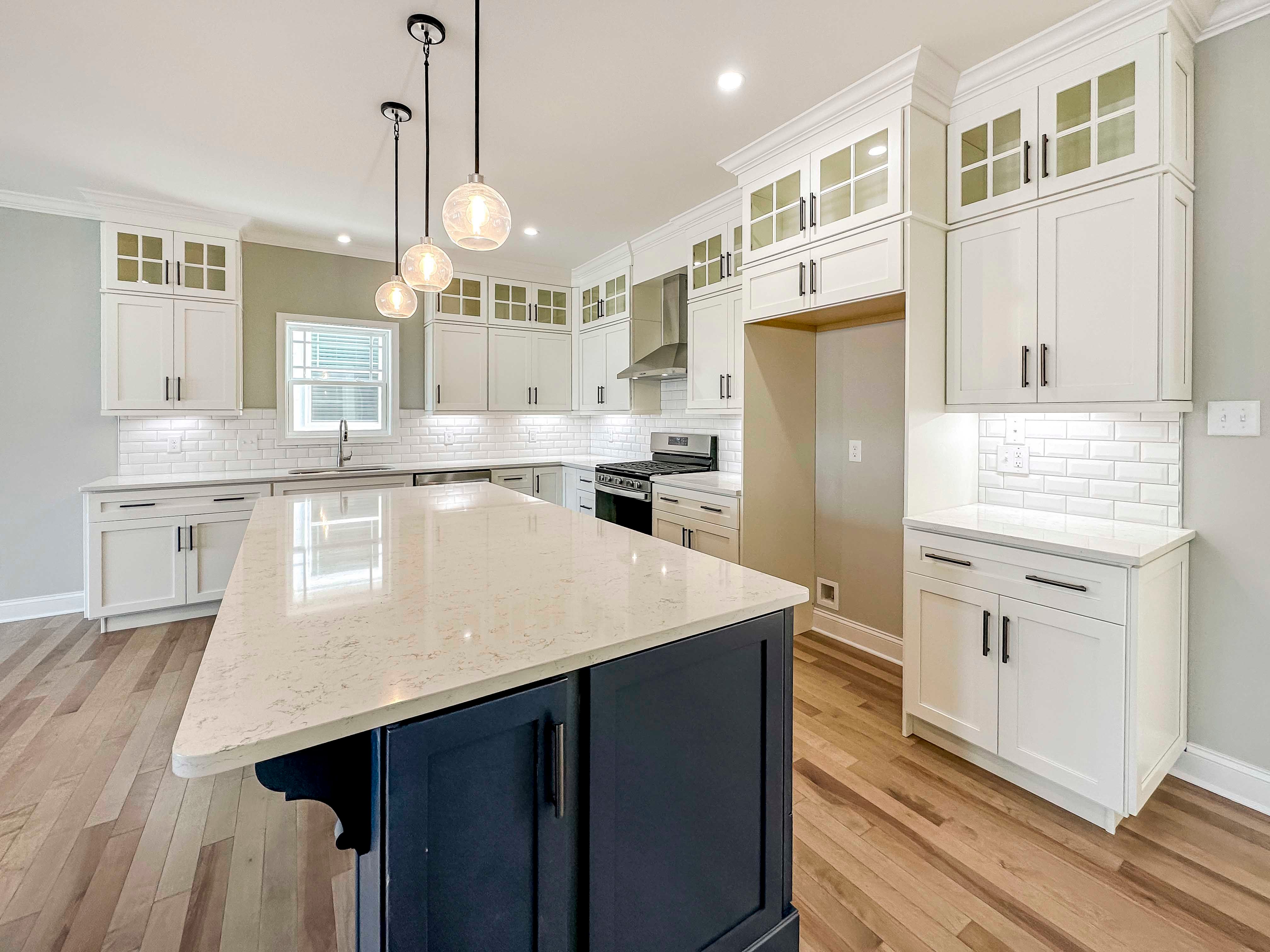 Kitchen with white quartz countertops, white cabinetry, and center island with blue cabinets.