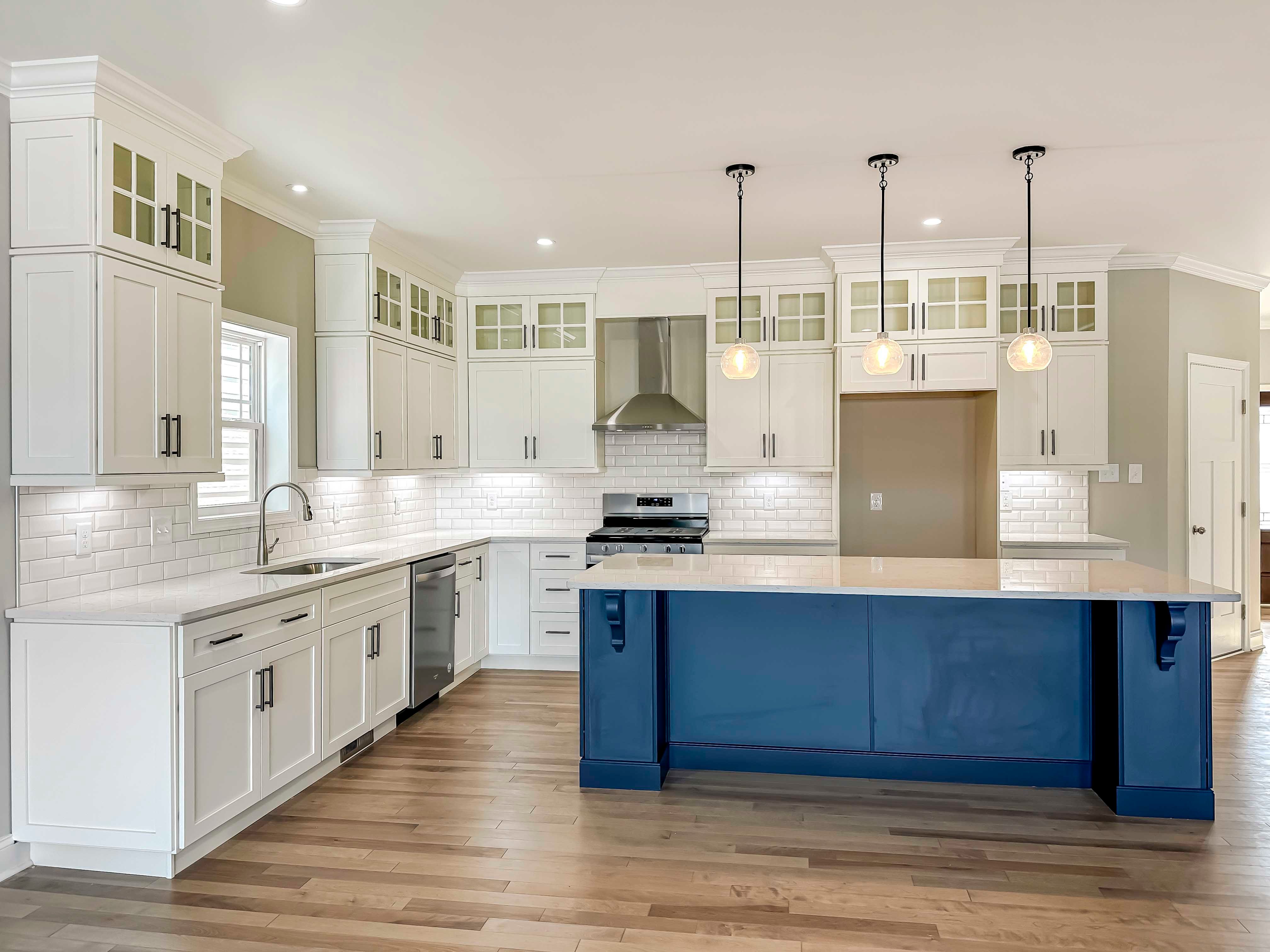 Kitchen with white quartz countertops, white cabinetry, and center island with blue cabinets.