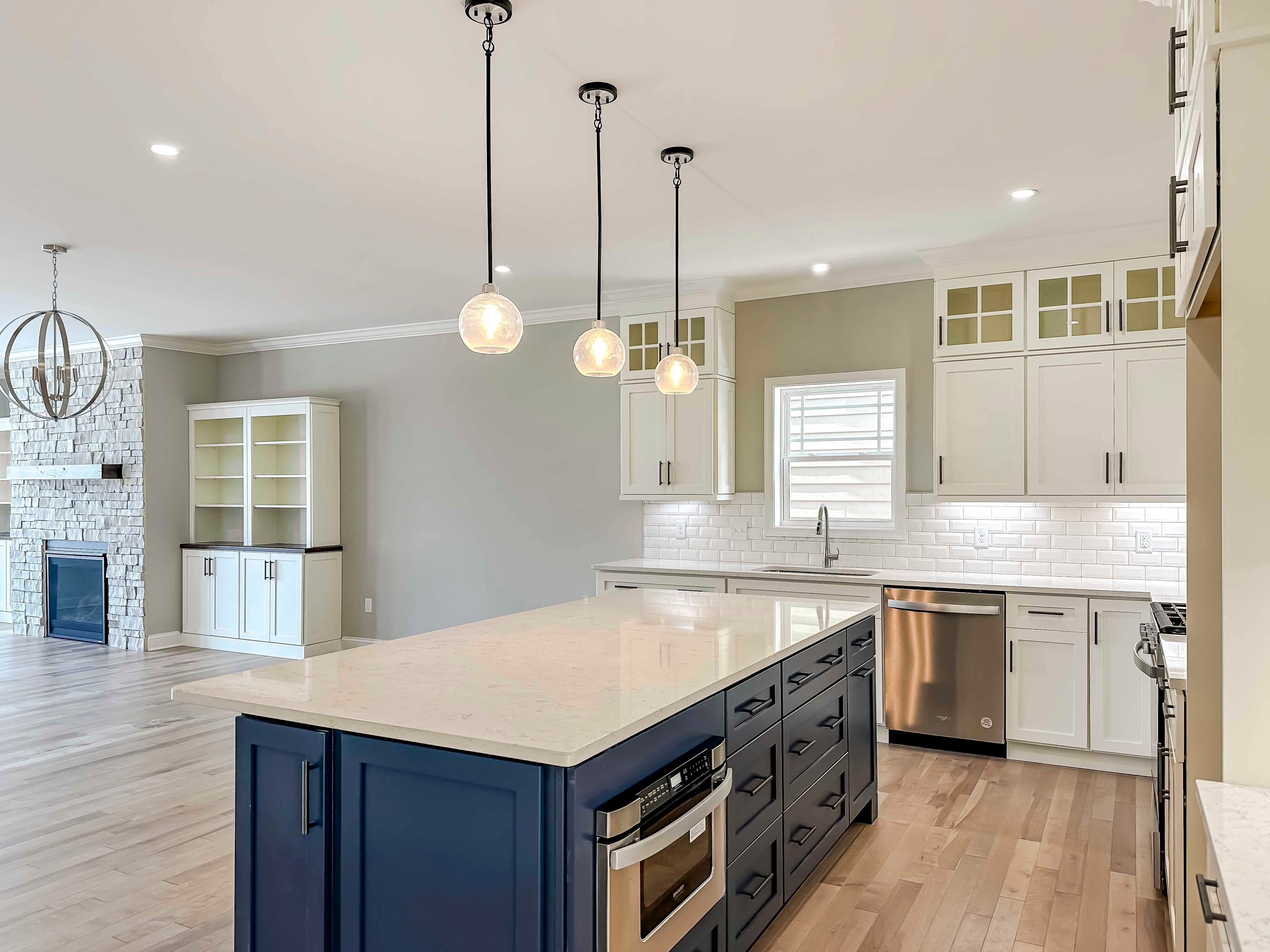Kitchen with white quartz countertops, white cabinetry, and center island with blue cabinets.