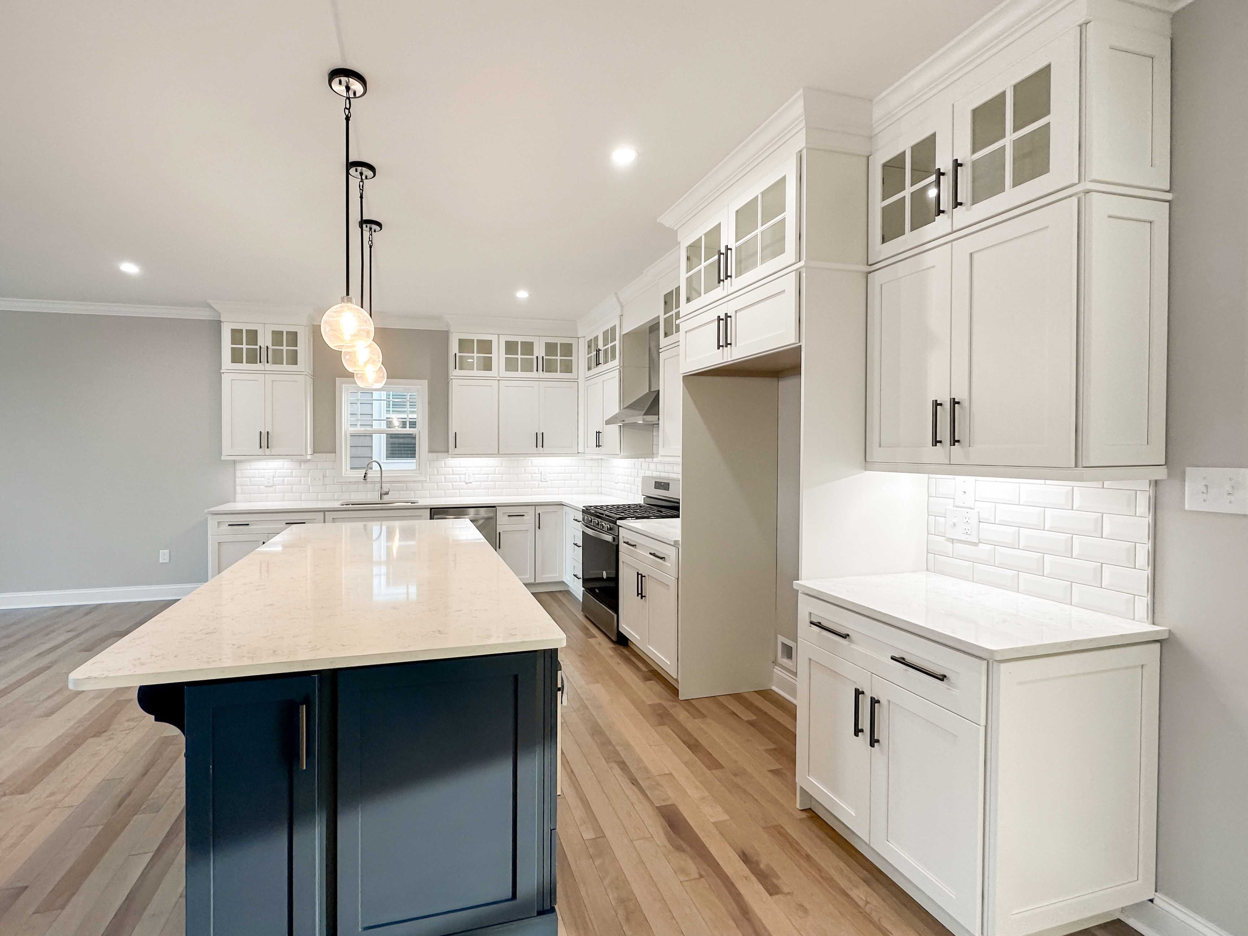 Kitchen with white quartz countertops, white cabinetry, and center island with blue cabinets.