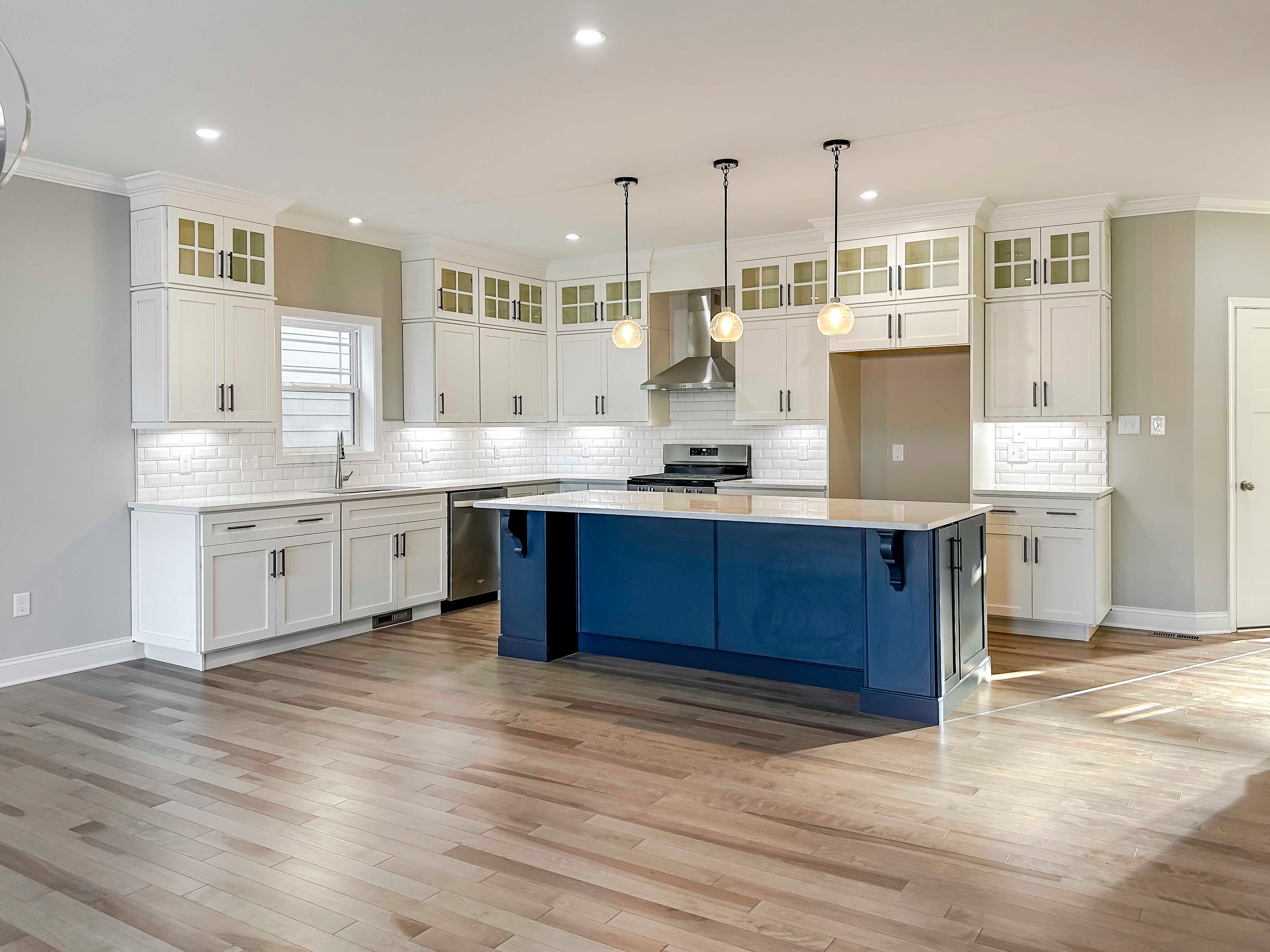 Kitchen with white quartz countertops, white cabinetry, and center island with blue cabinets.