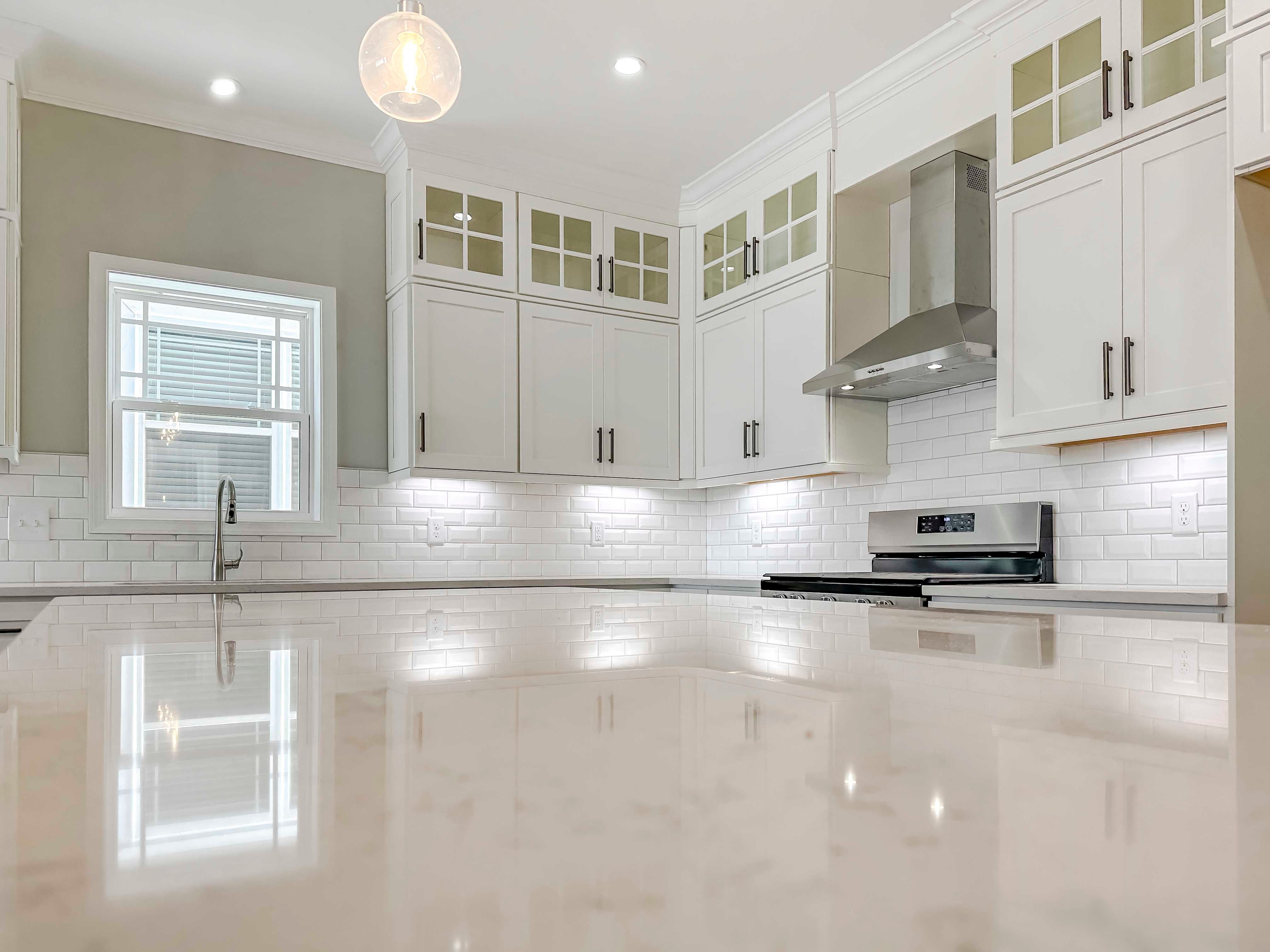 Kitchen with white quartz countertops, white cabinetry, and center island