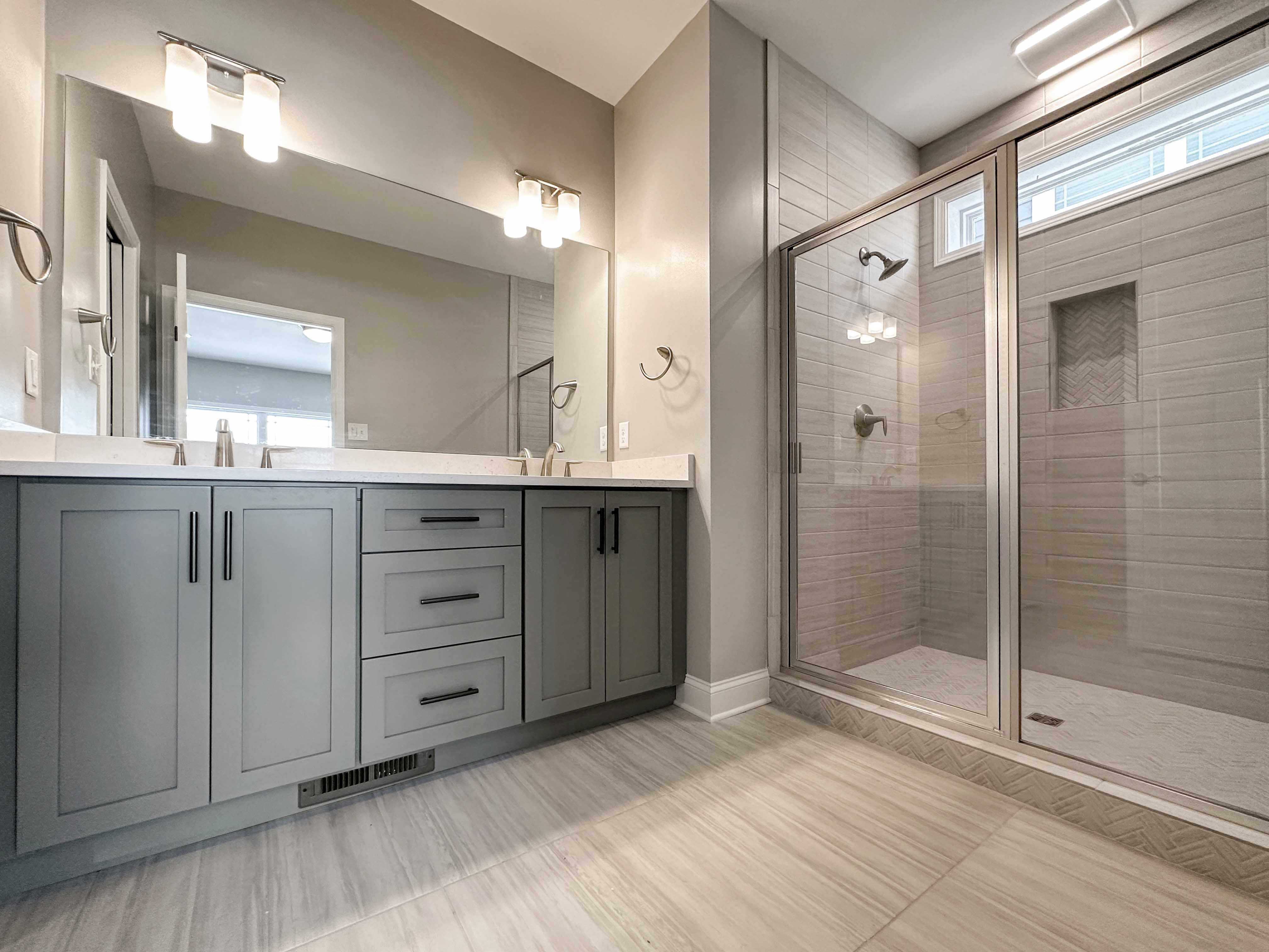 Bathroom with dual vanities, ceramic tile shower and floor