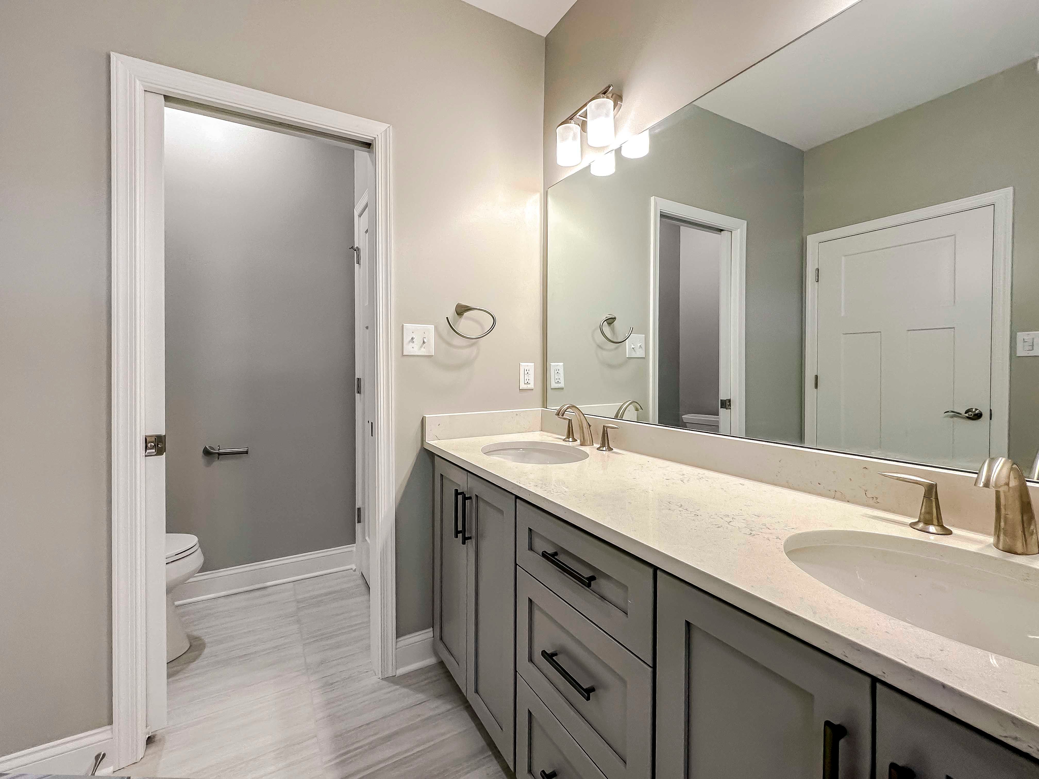 Bathroom with dual vanities and large mirror - facing doorway to water closet