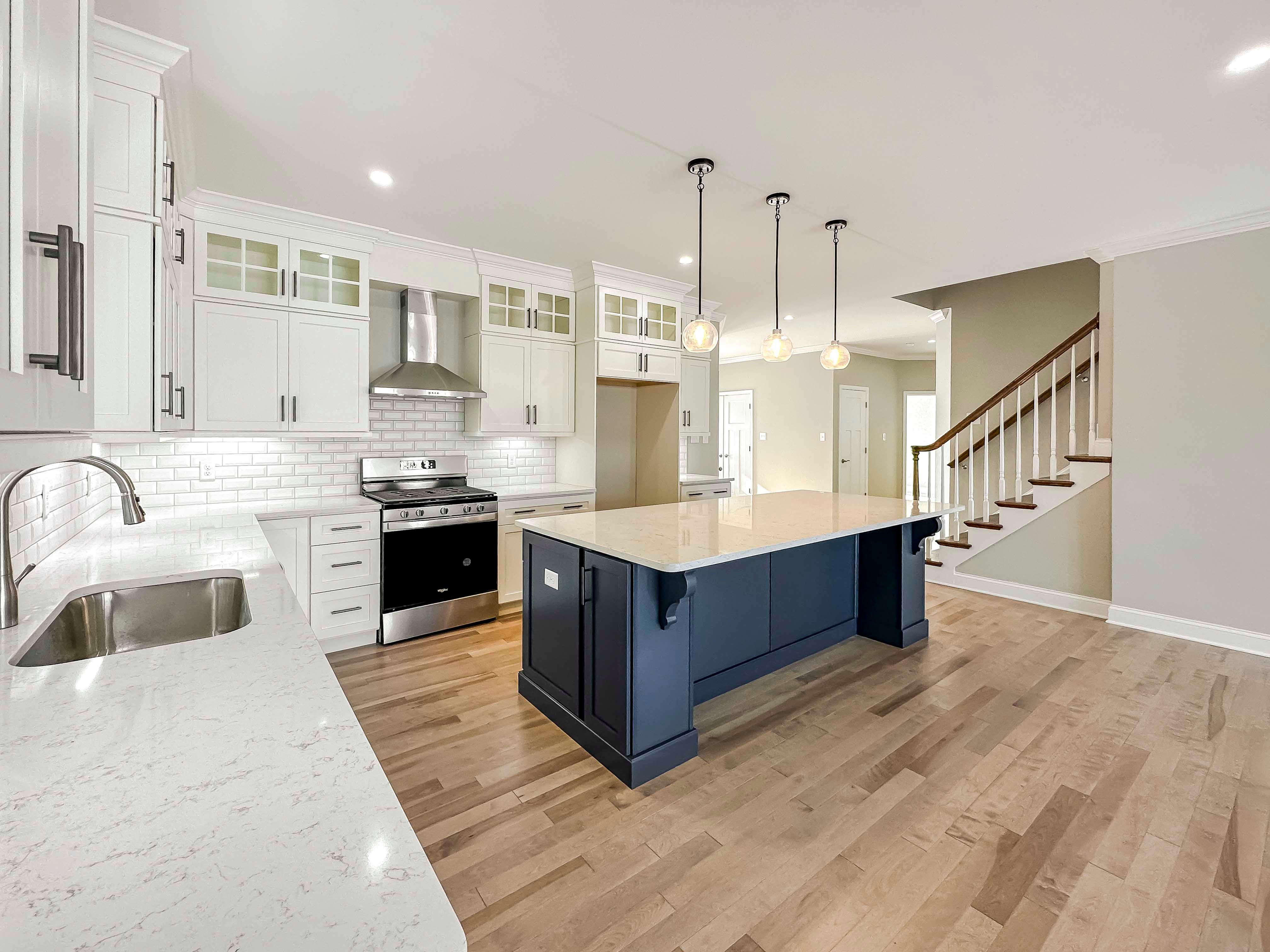 Kitchen with white quartz countertops, white cabinetry, and center island with blue cabinets.