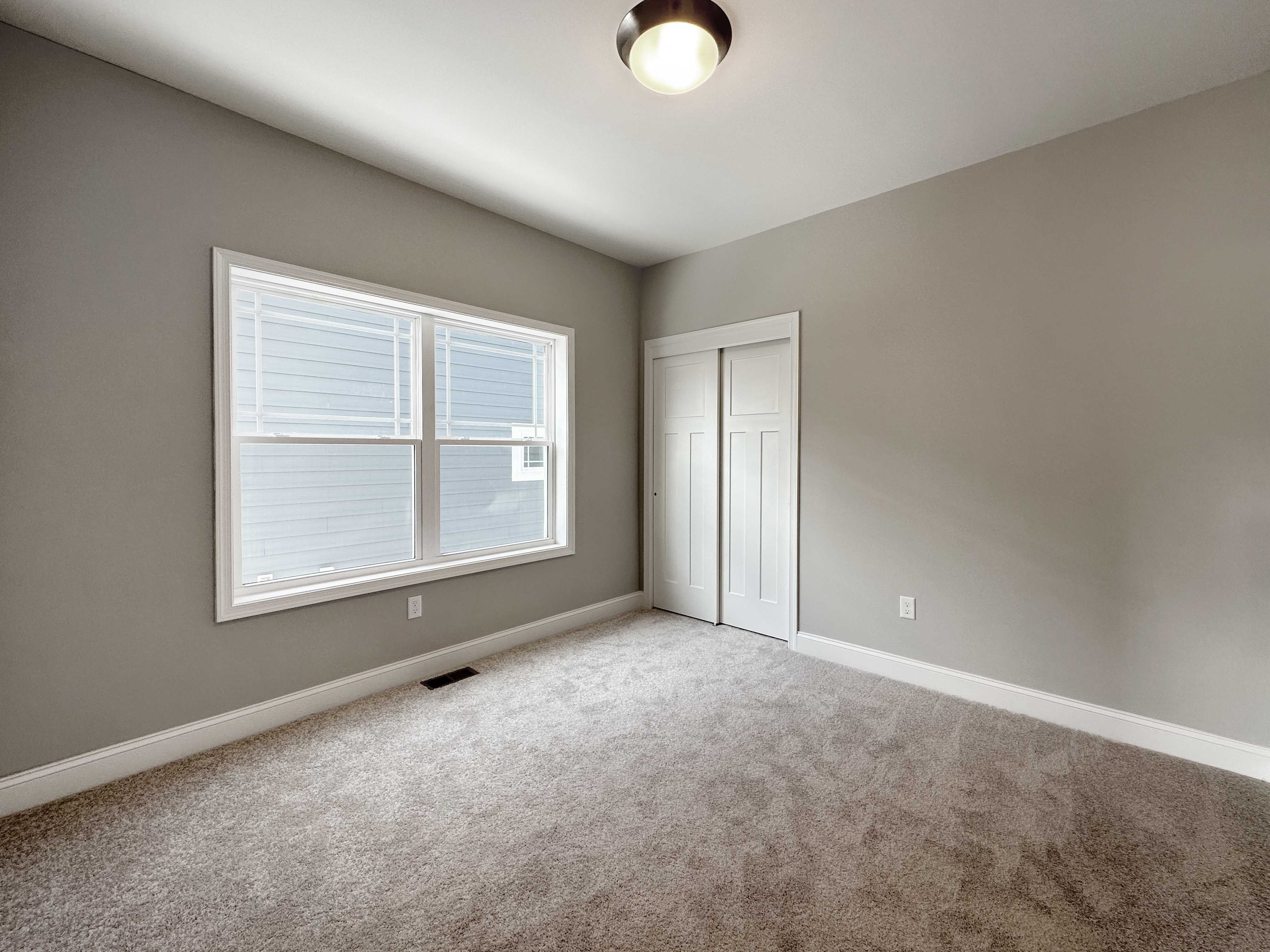 Bedroom with carpet flooring and two windows on side wall